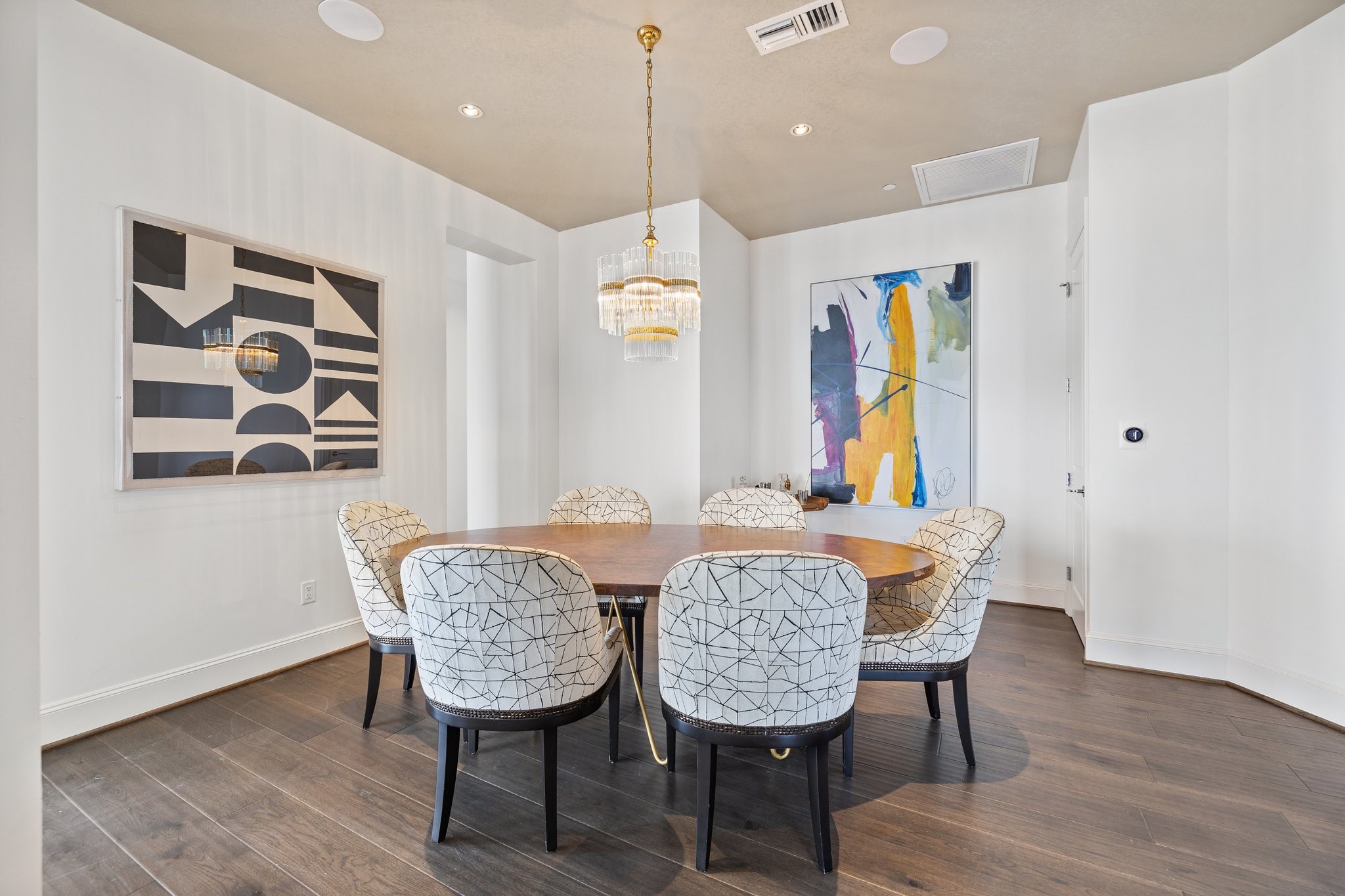 A perfectly placed dining area with a beautiful glass chandelier, new wood floors, and freshly painted white walls provides a sophisticated feel.