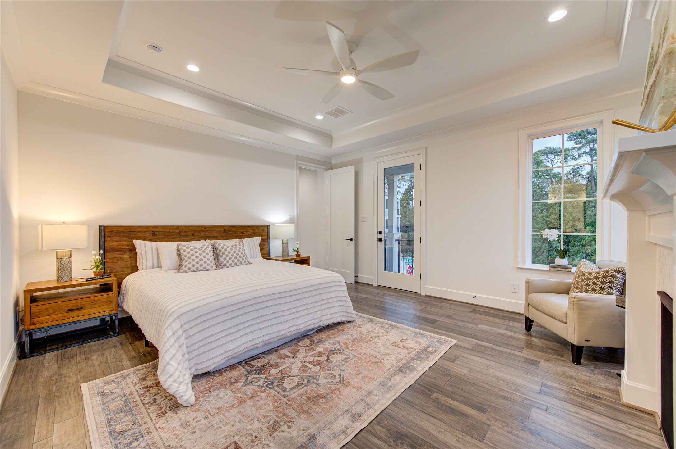 A spacious second floor primary bedroom boasts coffered ceilings, lots of windows, and wood floors.