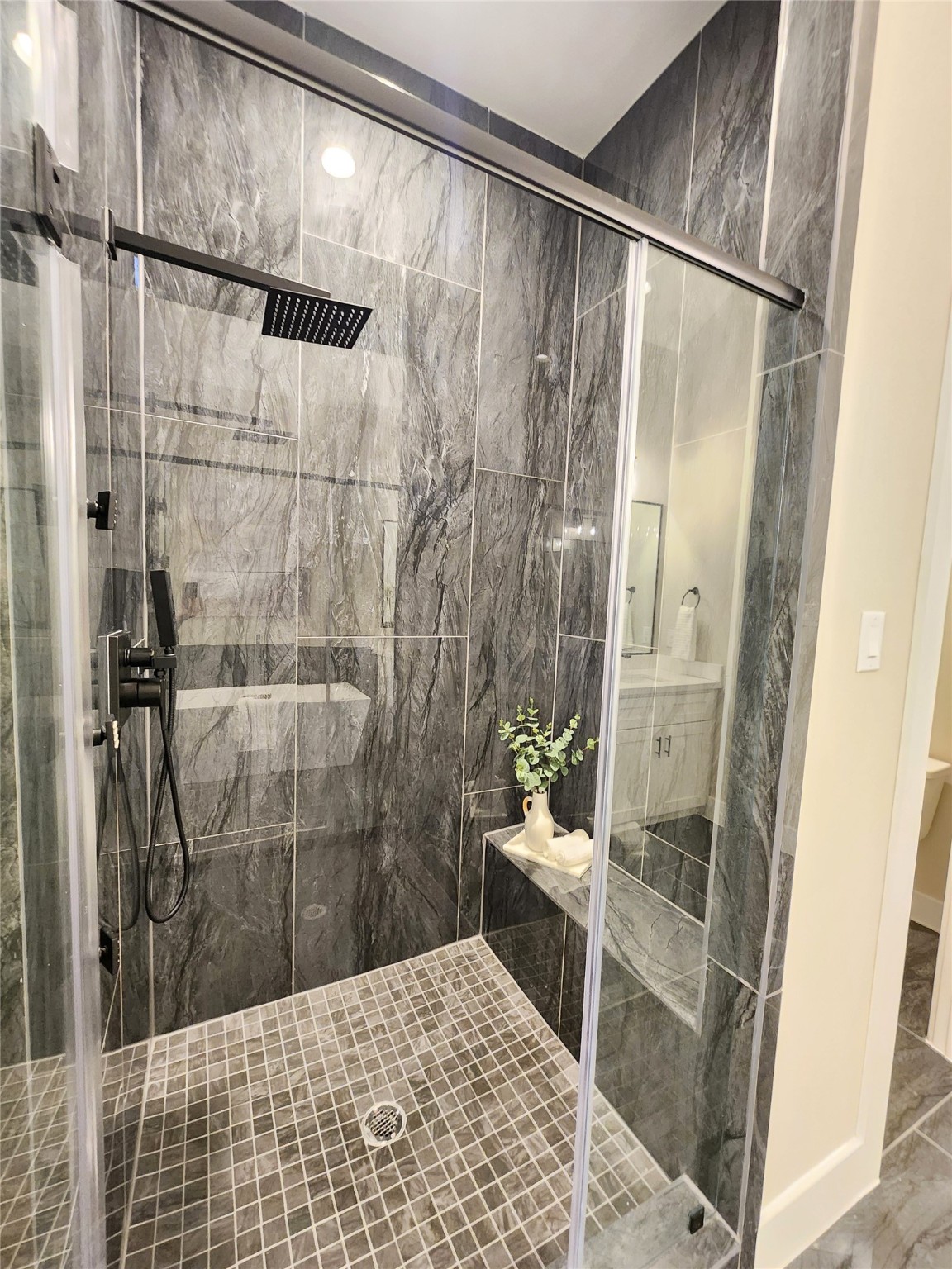 Stately shower with floor to ceiling porcelain tile and custom bench