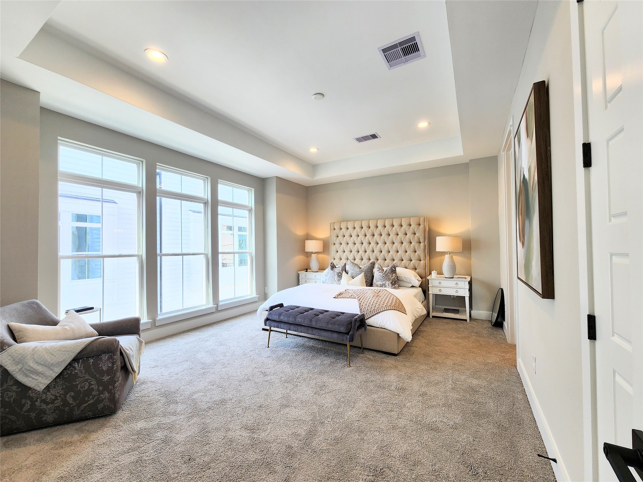 Spacious primary bedroom featuring a stately coffered ceiling with tons of natural light located on the second floor