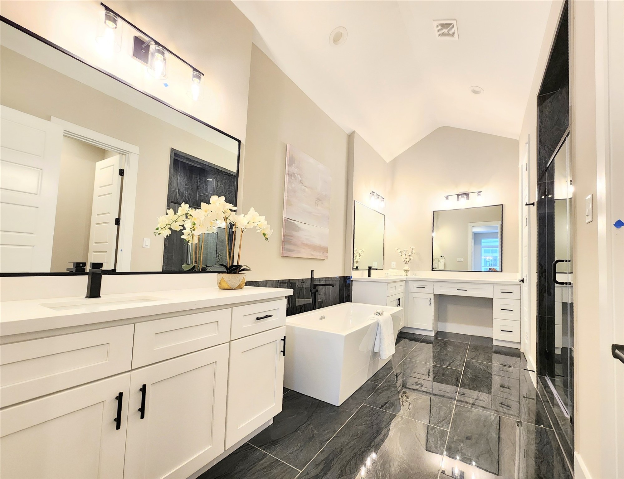 Stunning primary bath complete with vaulted ceiling, expansive double vanities separated by a n inviting soaker tub
