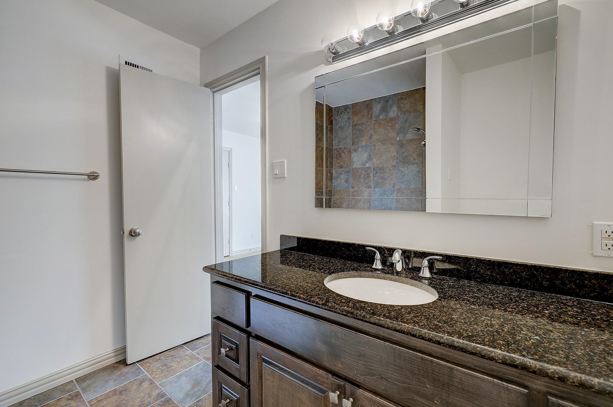 Alternate view of the full bathroom. Dark stained cabinetry, granite countertops with an under-mount sink and chrome plumbing fixtures, complete the space.
