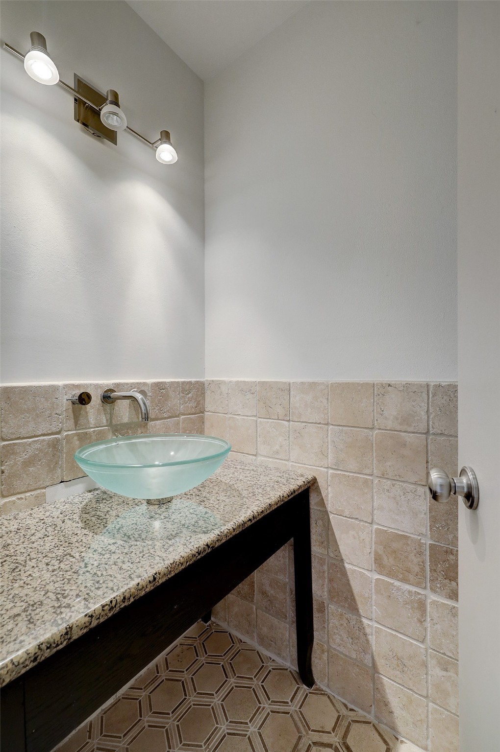 The powder bathroom is tucked away from view, but easily accessible to residents and guests. Granite countertops and a vessel sink are complimented by hexagon tile flooring.