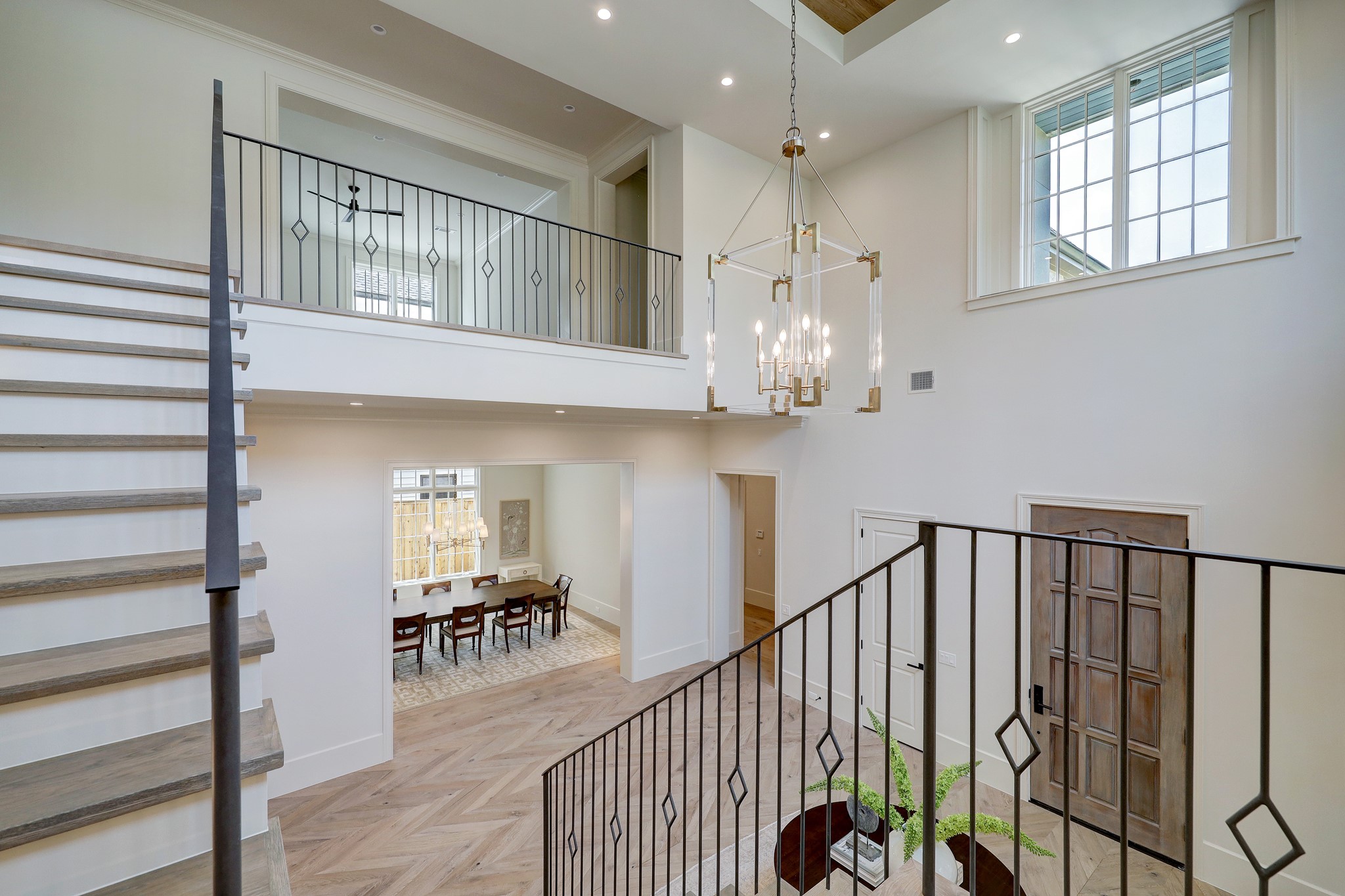 The opulent journey up the grand staircase with lit stair risers and gorgeous foyer light fixture by Hubbardton Forge.