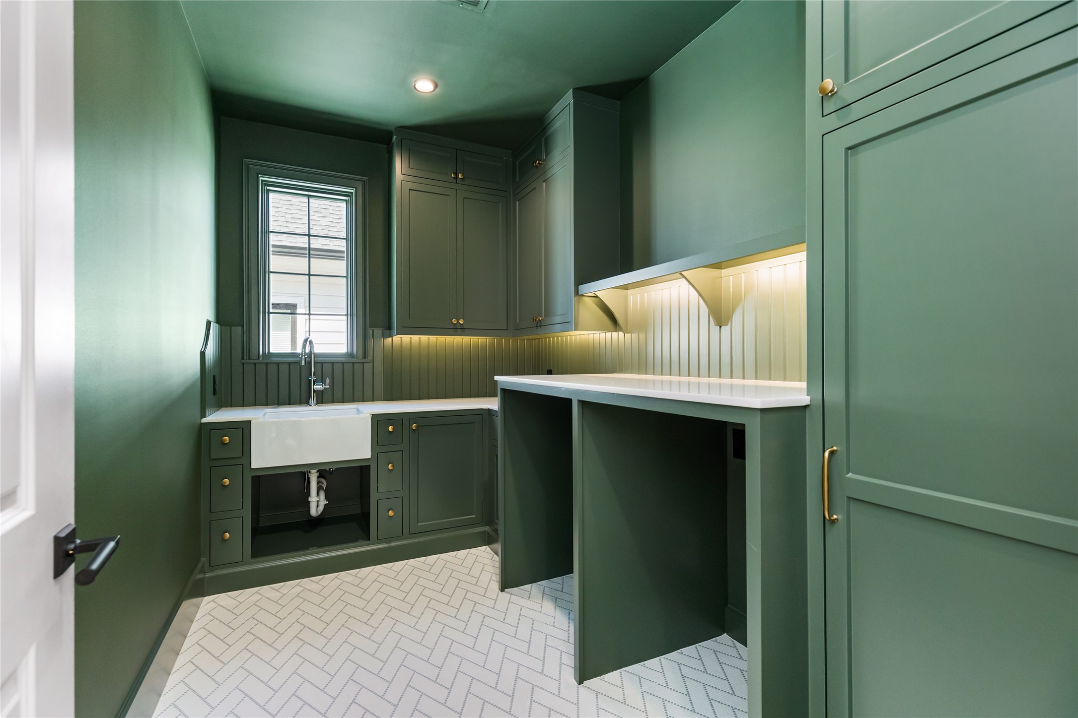 Laundry room is thoughtfully located on the second floor near primary and secondary bedrooms and features Harmonie Bridge recycled glass mosaic tile floor, tongue and groove backsplash detail, utility sink and Noble marble counter tops