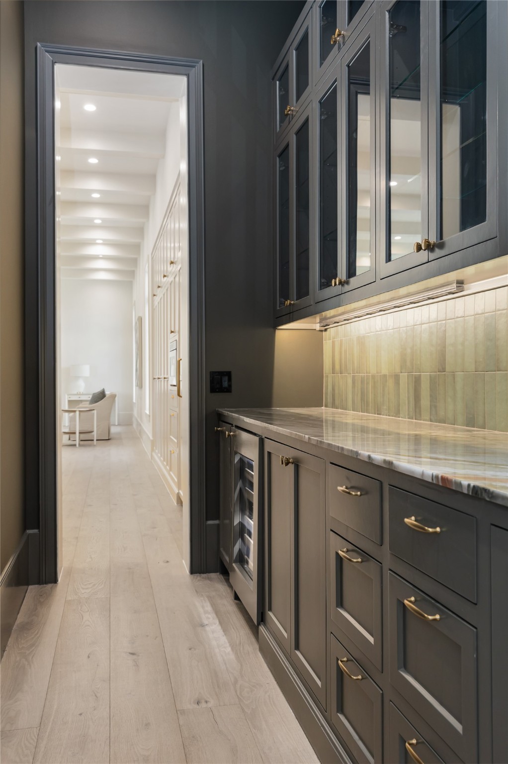Butler's pantry/bar offers an abundance of storage, including glass display cabinets, wine cooler, and marble countertop. The space is situated in between the formal dining room and the kitchen for easy entertaining.