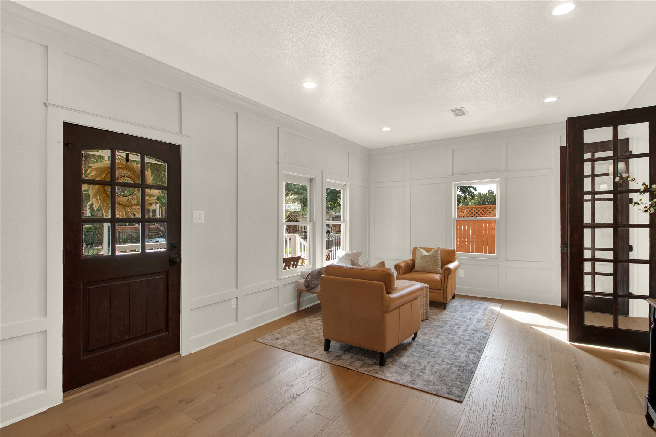 The original picture windows on three walls provide ample natural light.  Decorative millwork, recessed lighting and the imposing double French doors complete the space and compliment the vintage feel in this room.