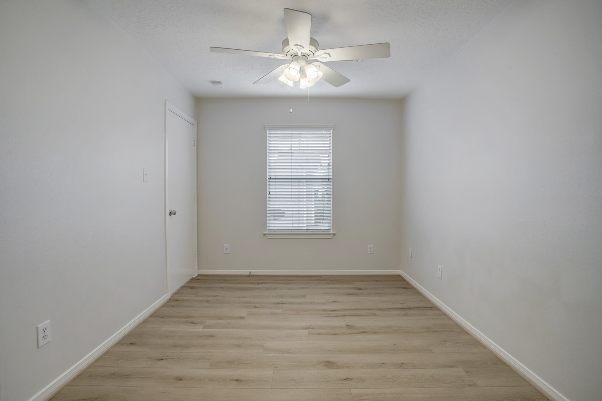 Another roomy bedroom with a large walk in closet, new floor, blinds and a ceiling fan.