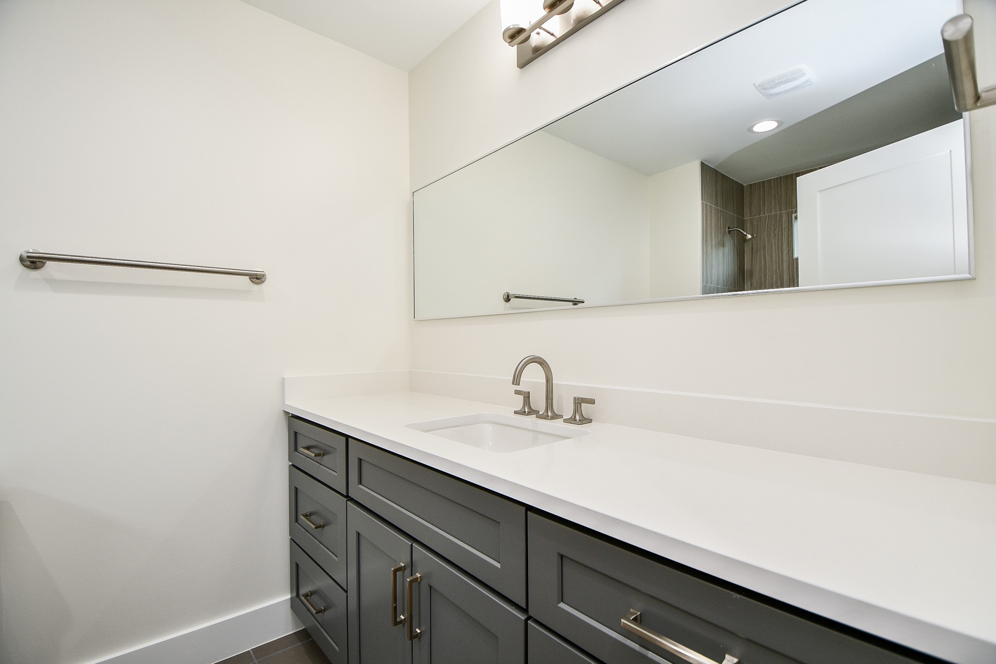 This trim, wall-wide mirror in a secondary bath is welcomed, over the length of a generous countertop!