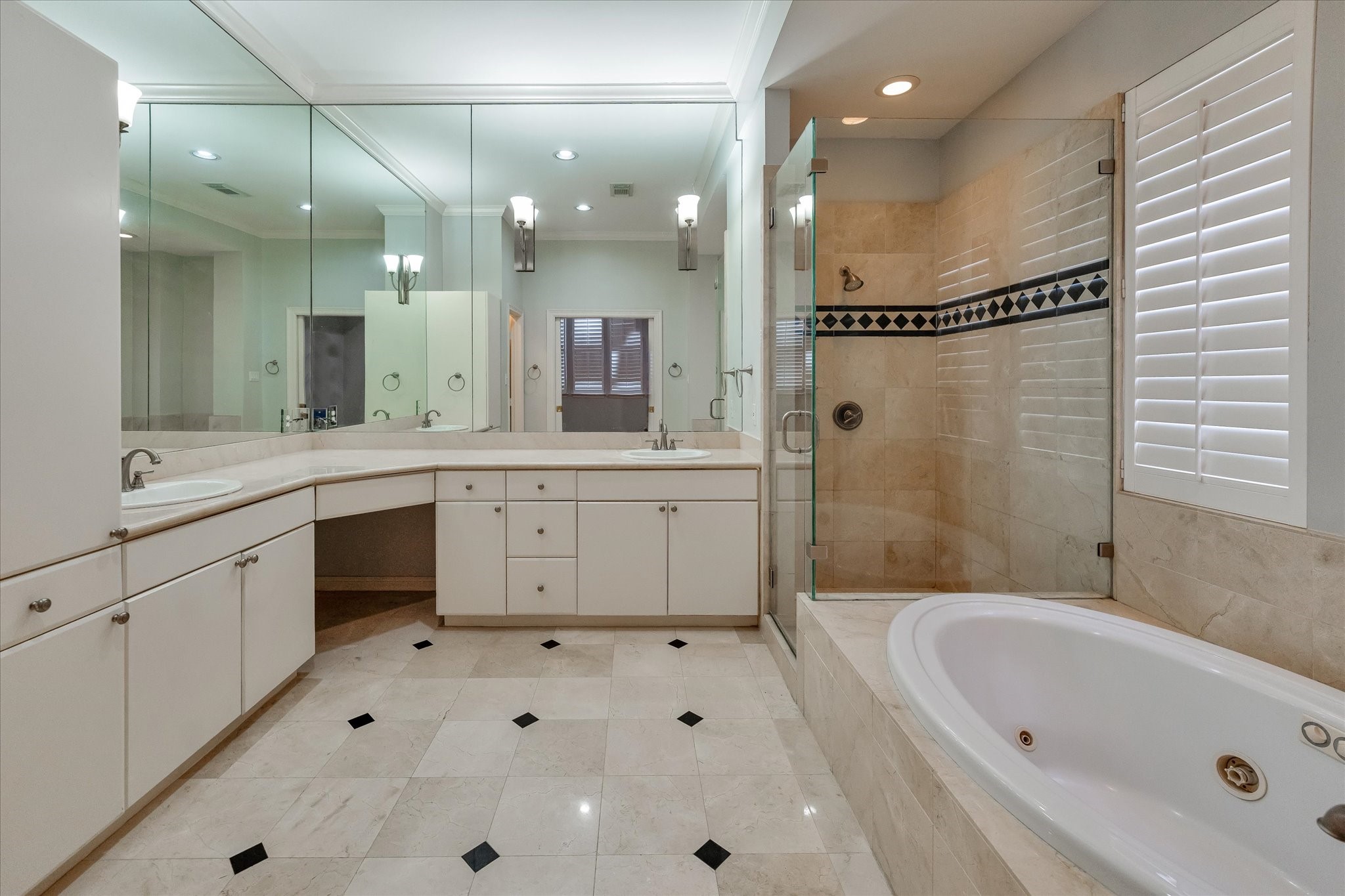 Your luxury primary bath is fitted with tile flooring, a large soaking and jetted bathtub, a double vanity, and a separate seamless glass walk-in shower.