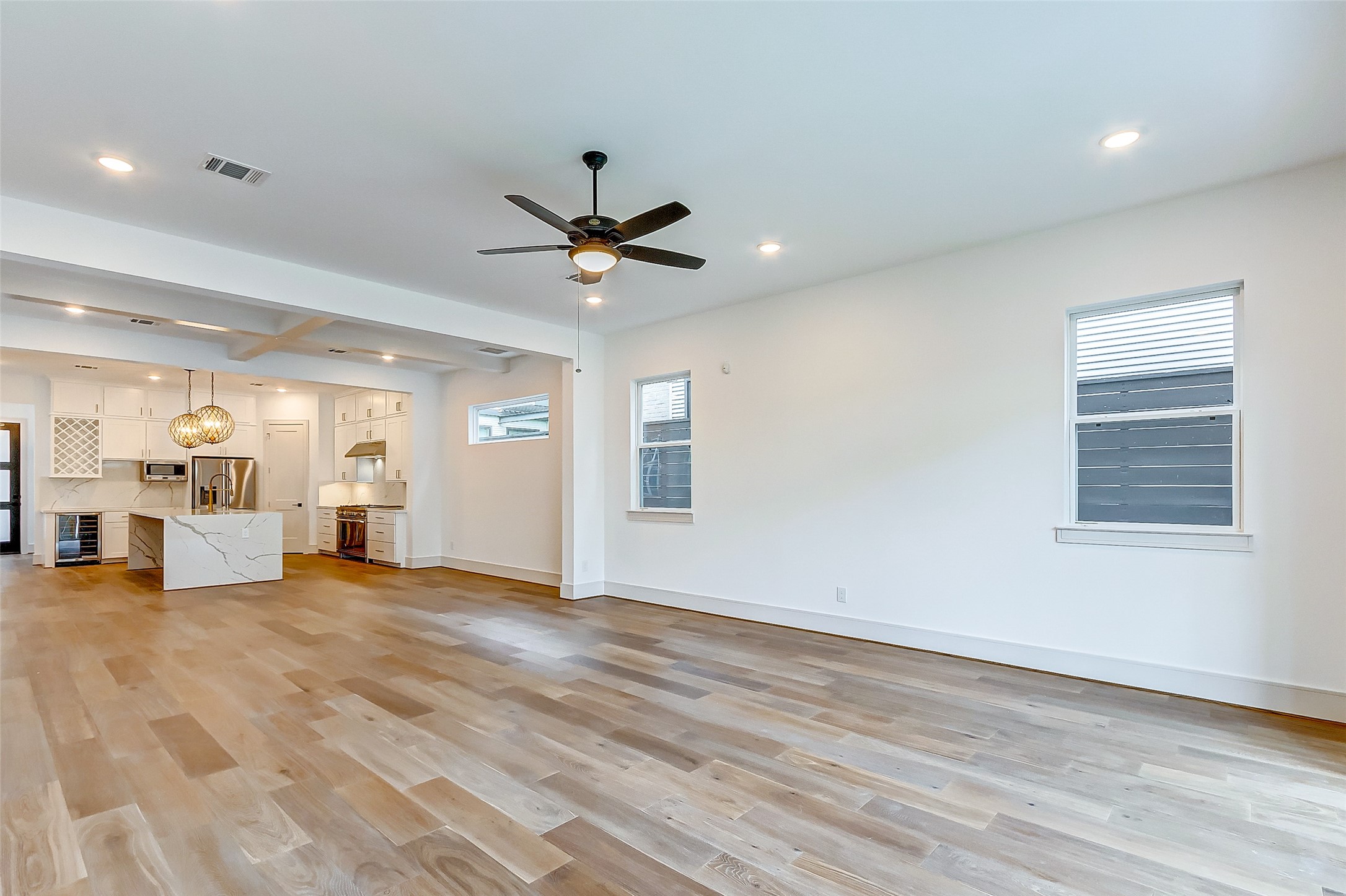 The family room sits adjacent to the kitchen and is SPACIOUS! Features of this large family room include designer paint, tall ceilings, a modern ceiling fan, bright windows, and hardwood floors.