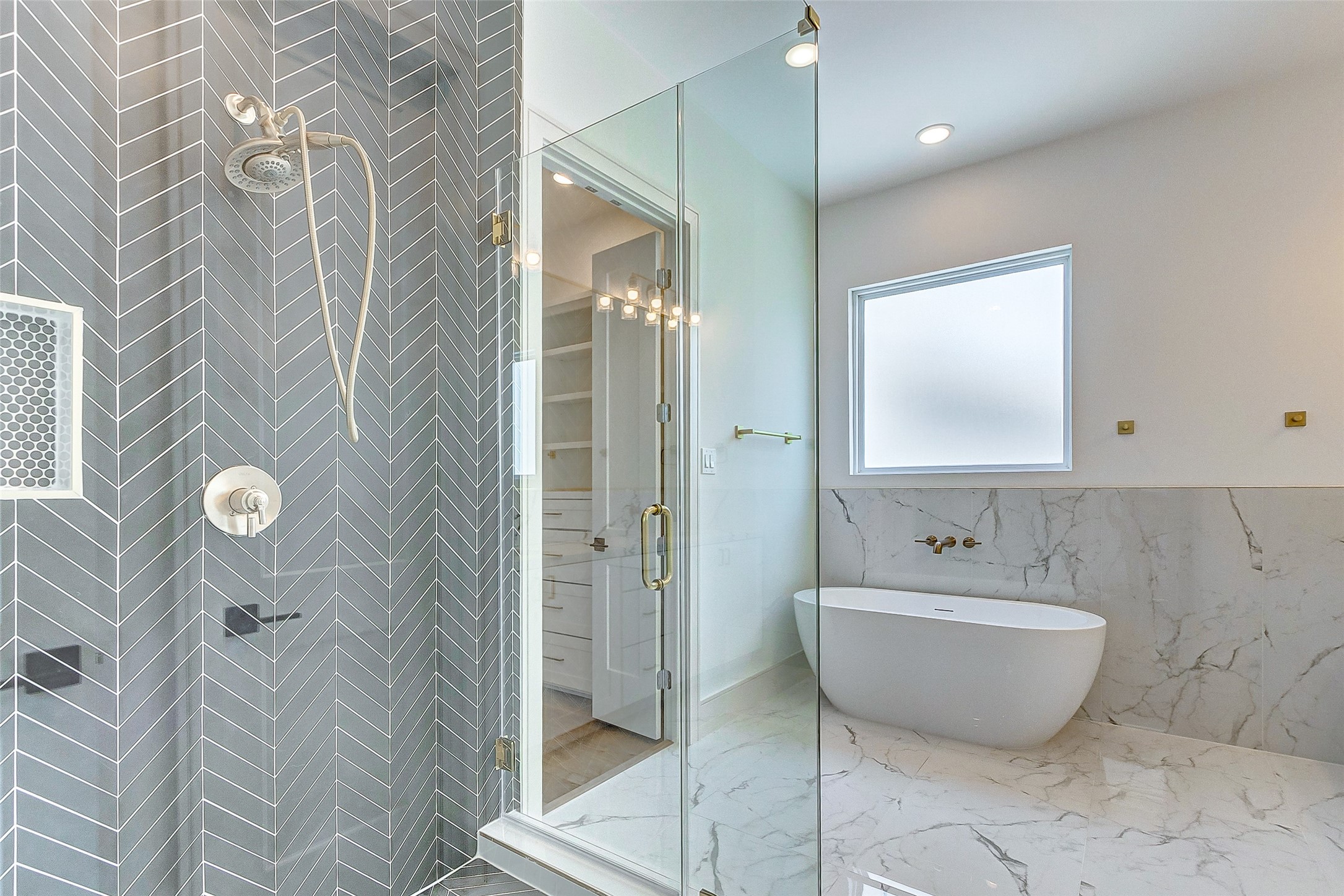 Step into your private primary ensuite bathroom to enjoy the luxe amenities offered. Features include white counters with coordinating white cabinets, dual vanities, gold hardware, a large mirror with vanity lighting, linen closet, privately tucked away commode, soaking tub, and walk-in shower.