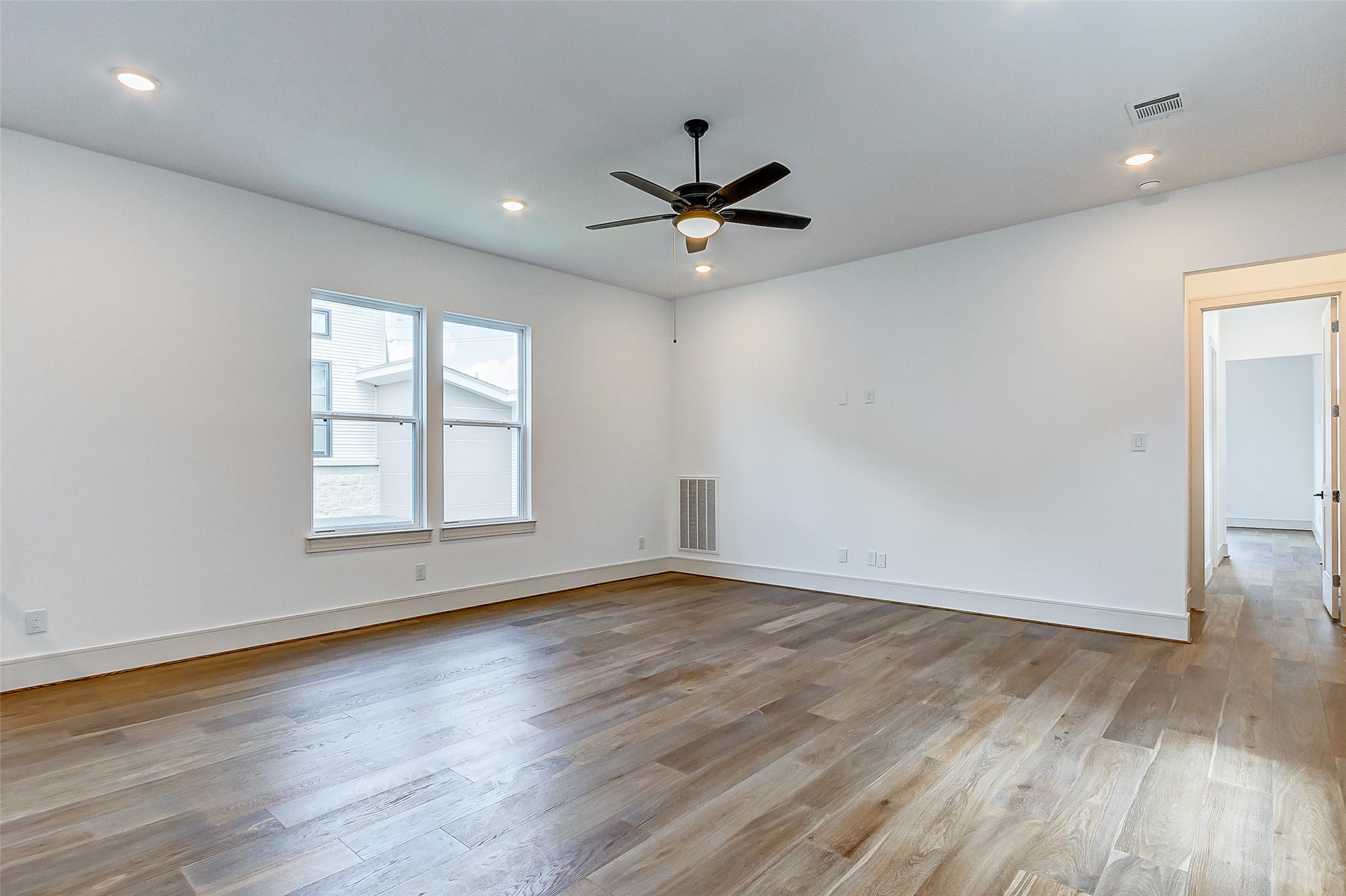 Upstairs, you'll find your spacious game room. Features include hardwood floors, designer paint, a modern fan, and bright windows.