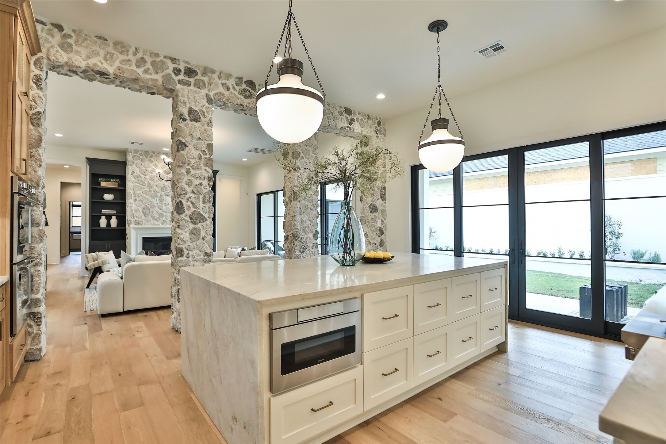 Two elegant designer pendant lights complement the island. The gas range is a Fisher Paykel with 6 burners and a griddle plus a pot filler and custom vent hood.