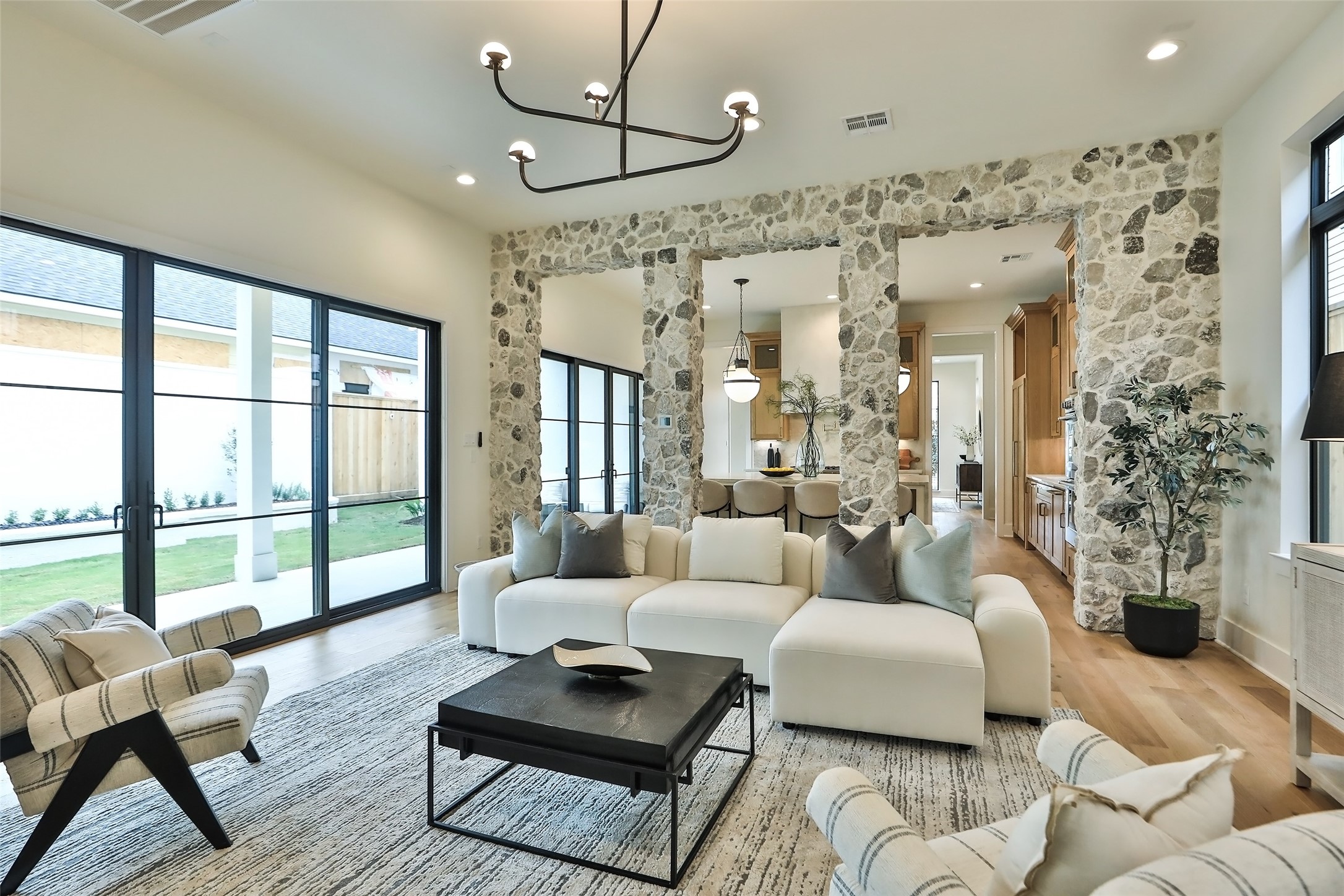 The living room has a wall of glass with Marvin Fiberglass patio doors that open to the patio. The room has an elegant chandelier to complement the White Oak wood floors.