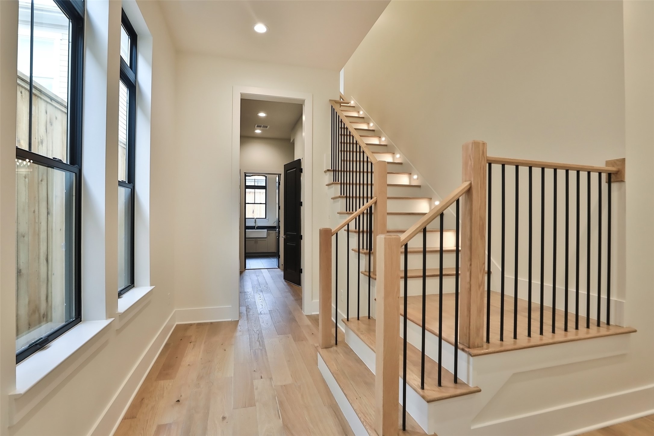The second stairs are in the back of the home with lighting every other step. In the distance is the mud room, laundry room, second half bathroom and​​‌​​​​‌​​‌‌​‌‌​​​‌‌​‌​‌​‌​​​‌​​ garage.