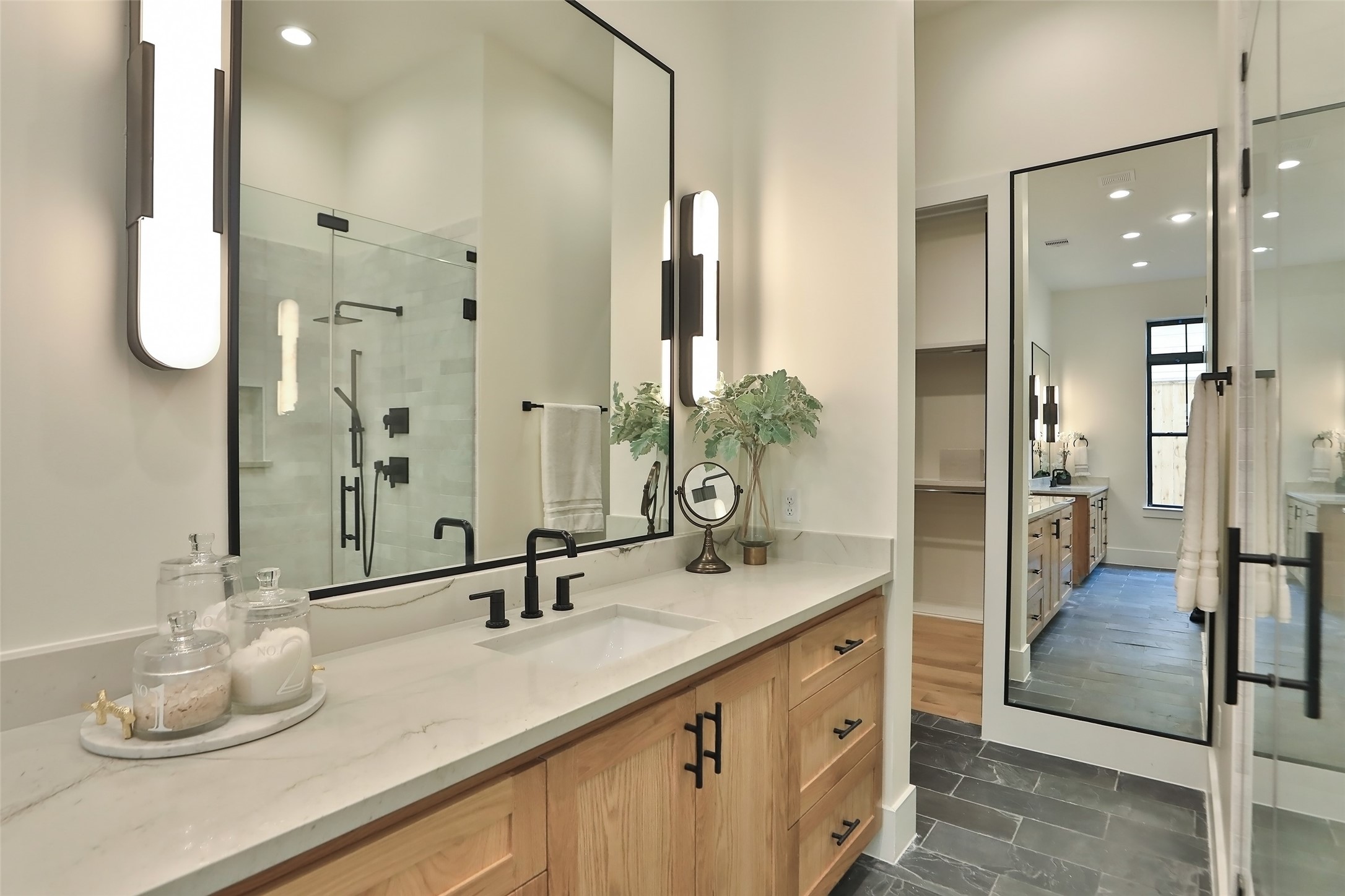 The primary bath has a huge walk in shower and separate soaker tub with flagstone tile floors and large full length mirror.