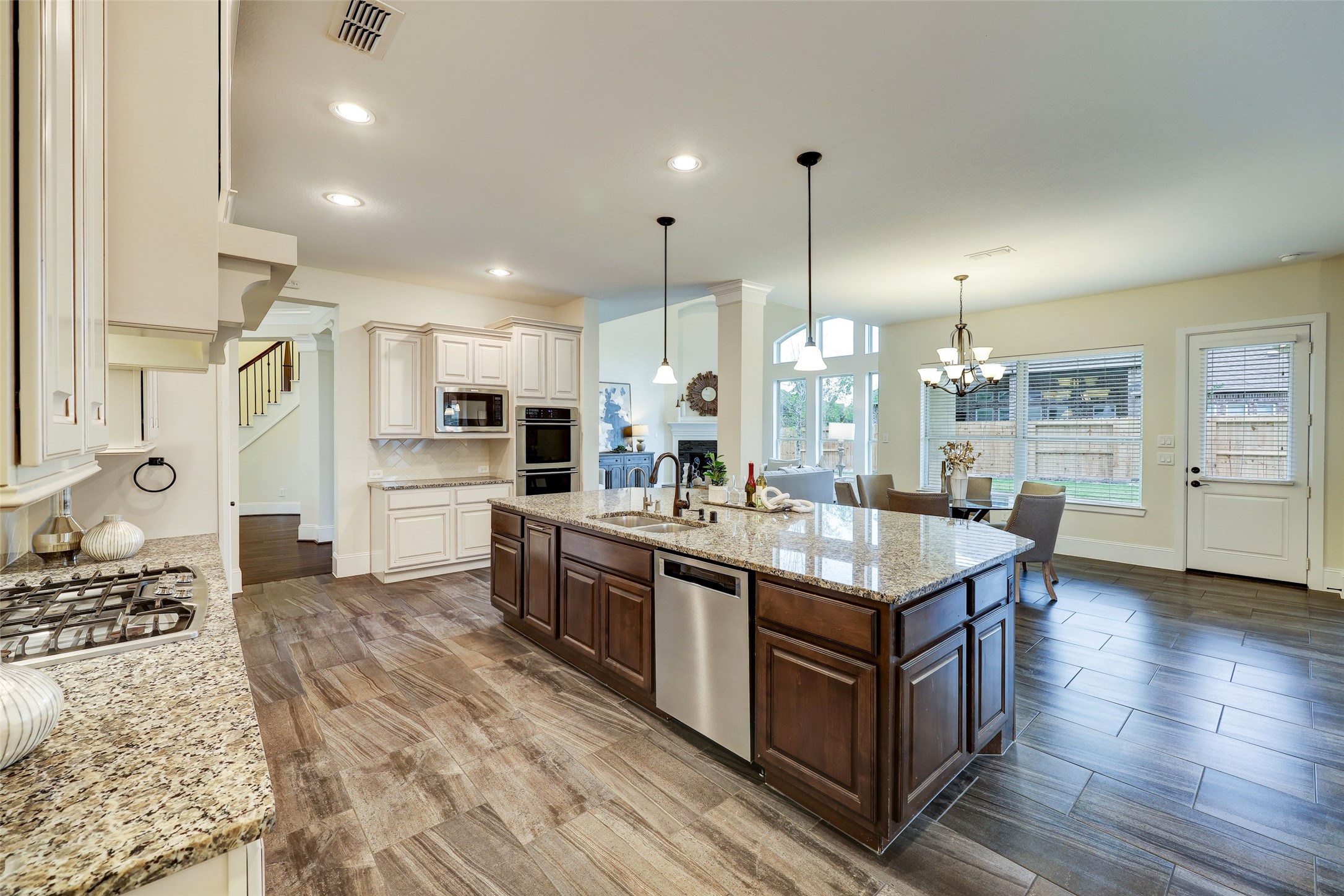 An additional angle of the kitchen peering into the family room and breakfast area showcases the depth of this generous first floor layout. A second bedroom suite is to the right of the patio door.