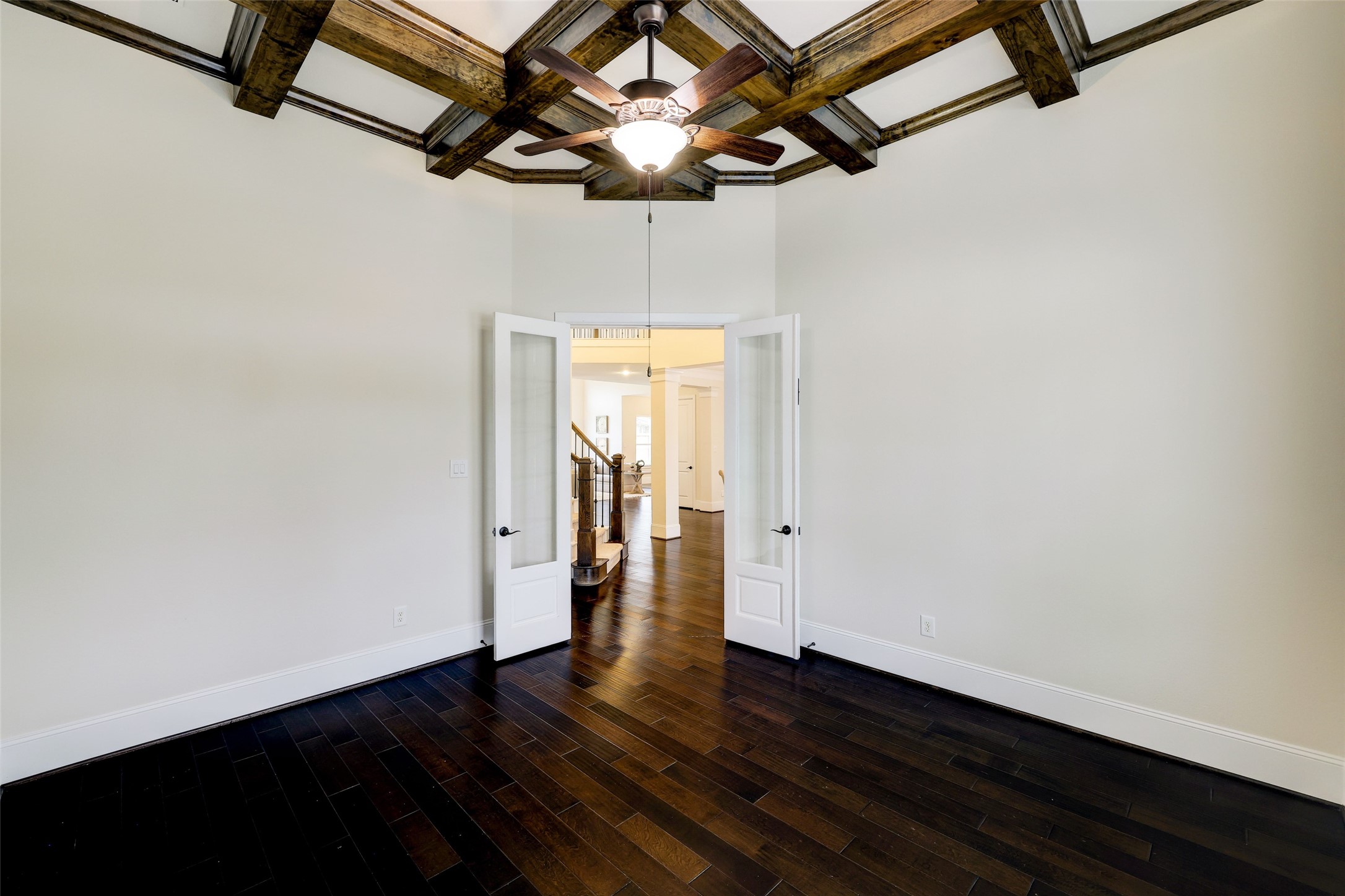 Double French doors provide privacy, while the dark wood flooring and wood coffered ceiling provide add richness to the space.