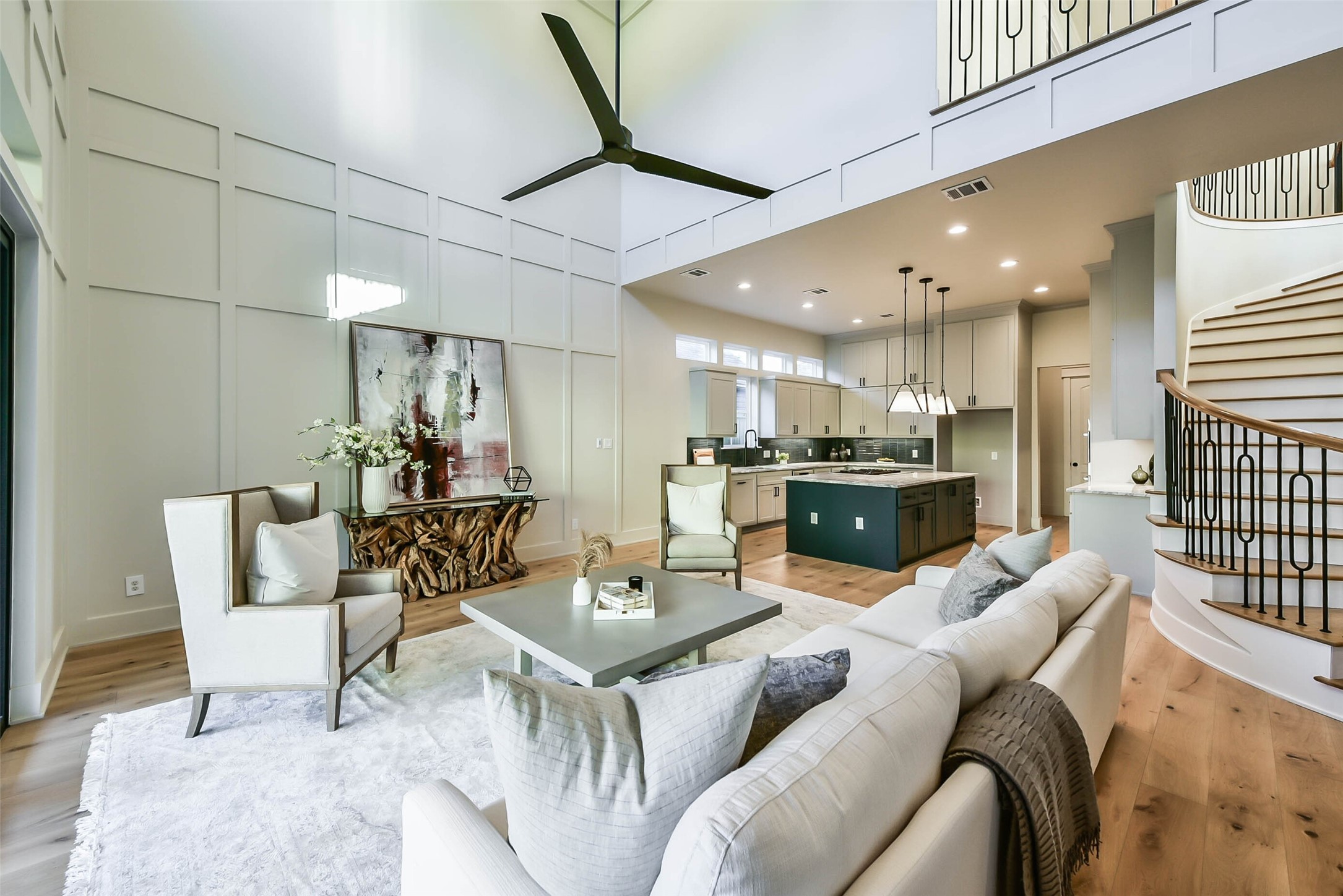 The great room is open to the kitchen and features two story ceilings, wainscoted walls custom wrought iron railings from the balcony above and high windows creating a light and bright atmosphere throughout the first floor.