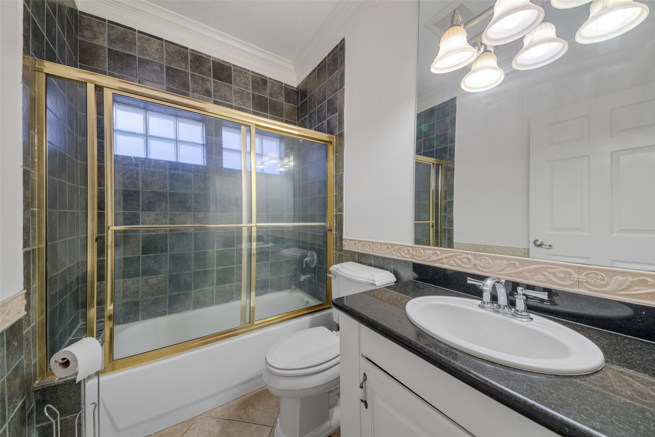The classicly designed upstairs bathroom showcases a glass door shower-tub and granite counter tops.