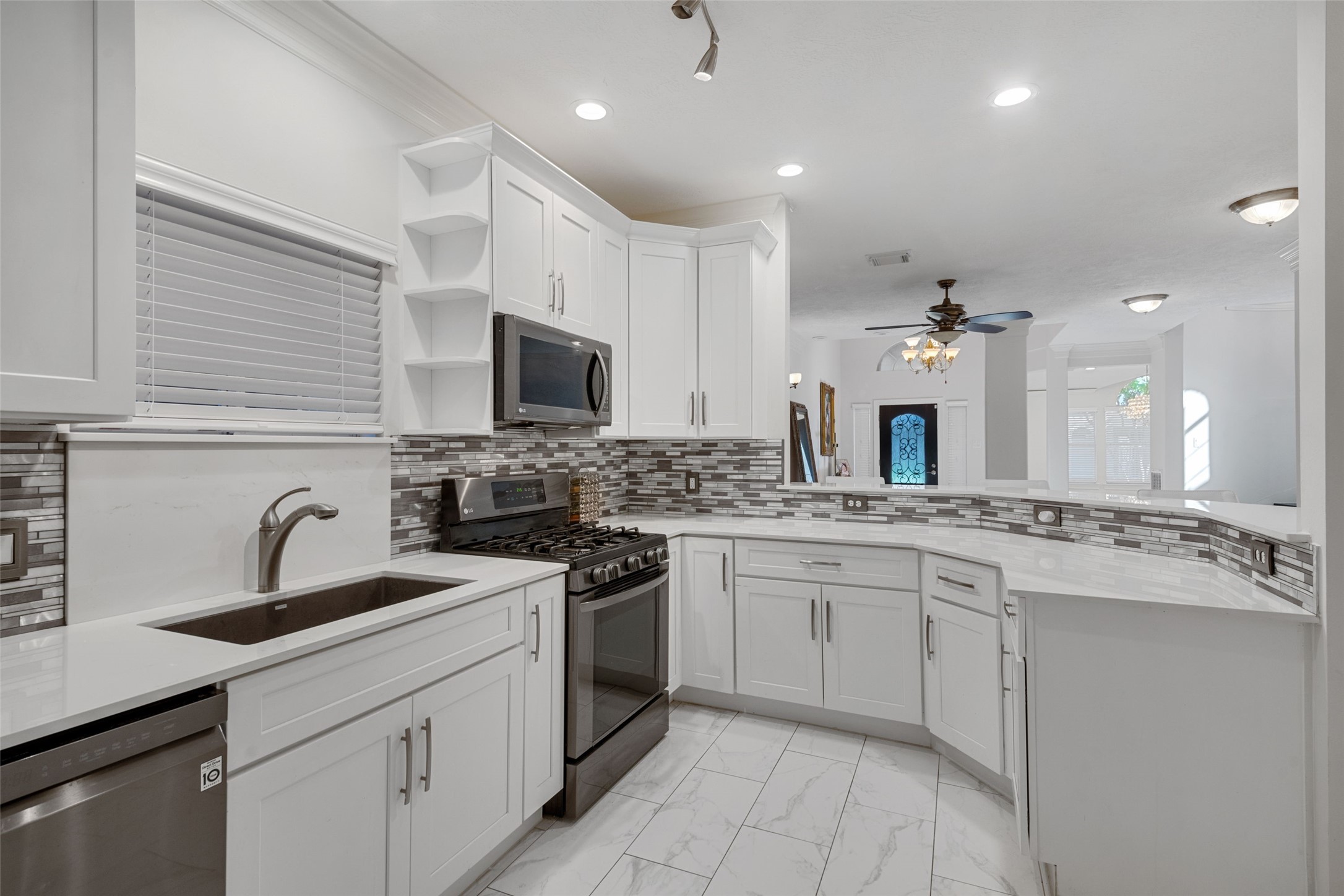 The kitchen is beautifully designed, with sleek quartz countertops, a back splash to complement the white cabinetry and black stainless steel appliances.
