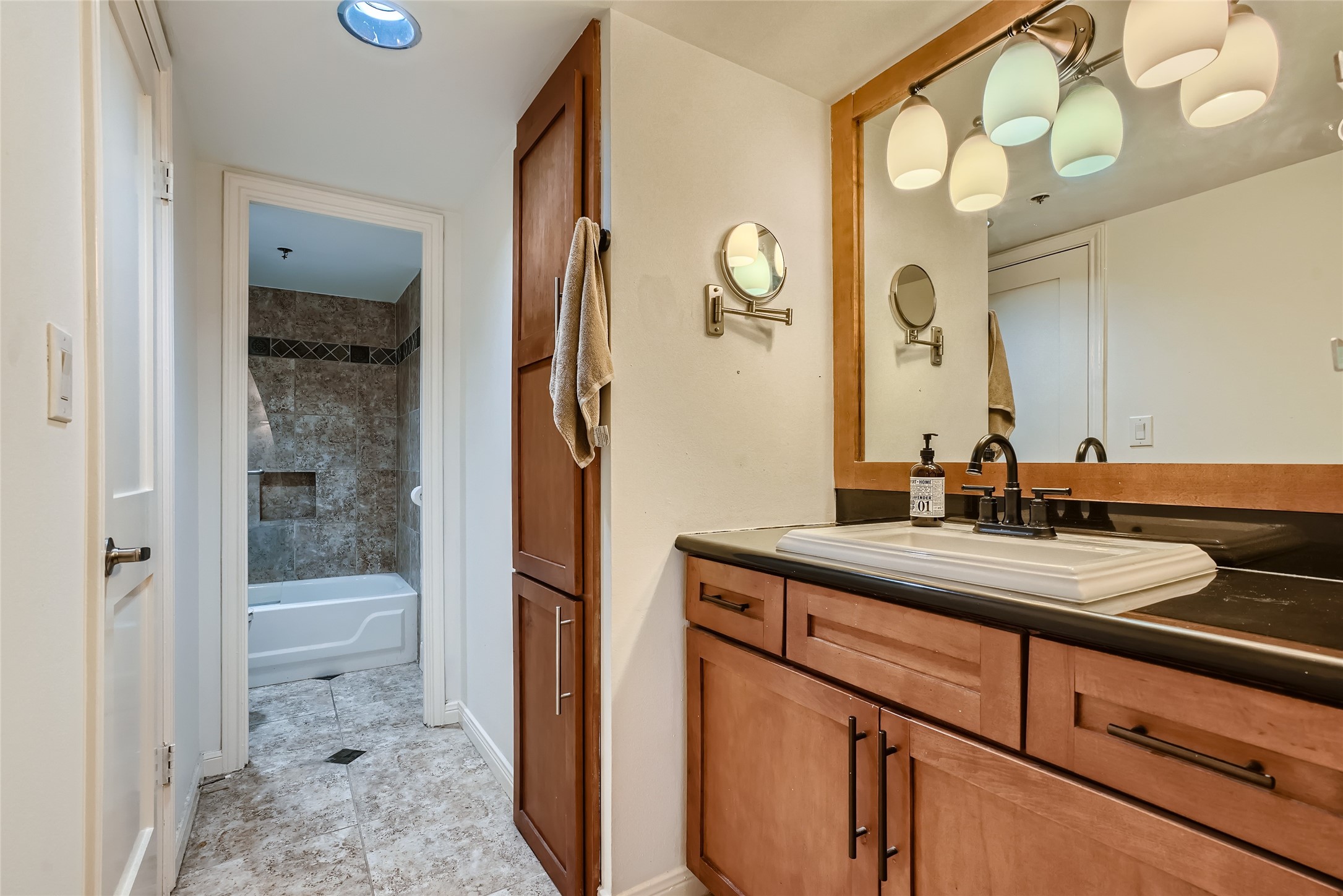 This carefully curated primary bathroom is ideal for your daily routine. A walk-in closet is to your left and extra storage for linens and toiletries is to the right. It includes a custom vanity, mirror and granite counter tops.