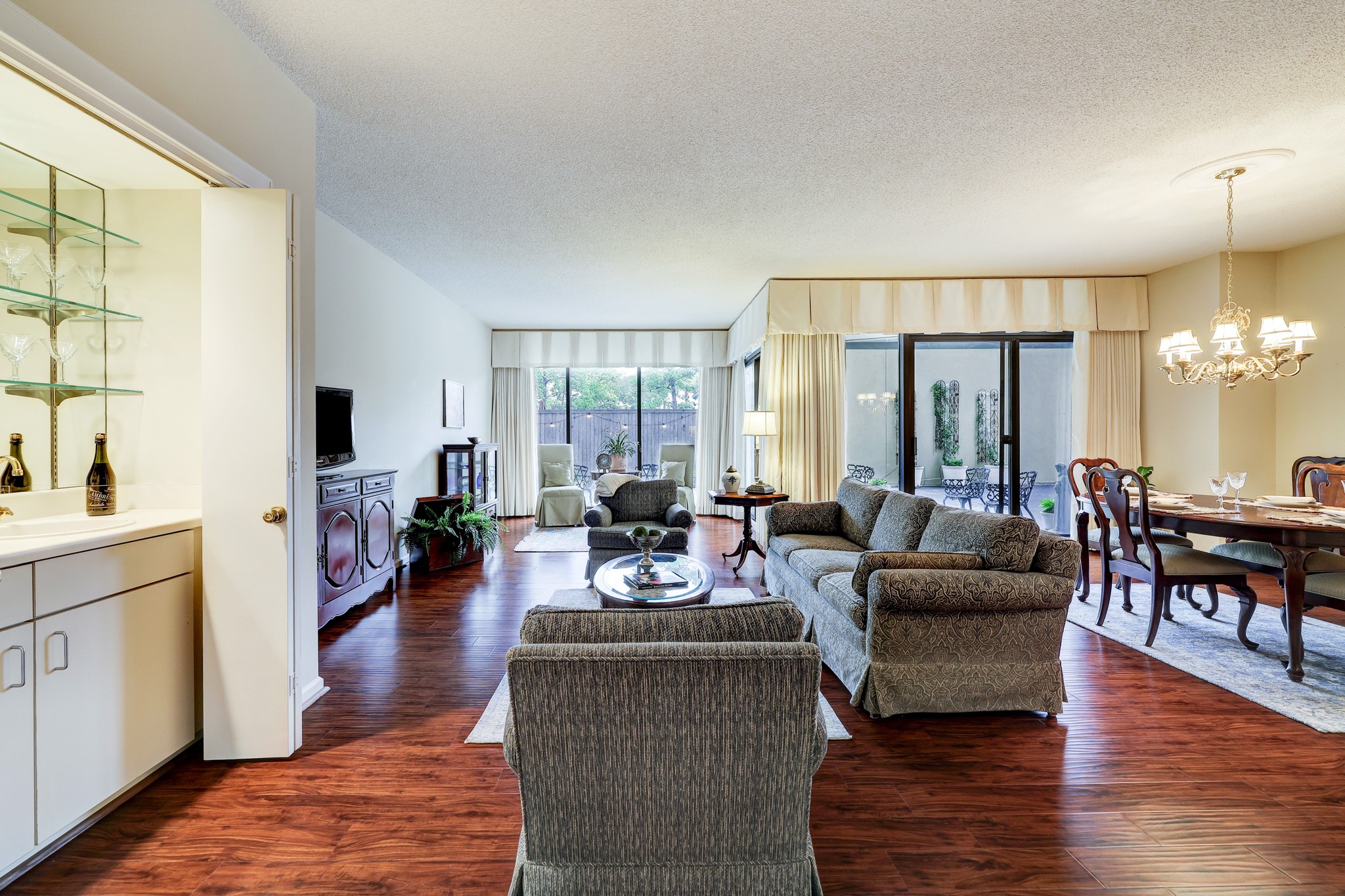 Living area has additional seating area near the full-length windows and sliding glass doors.