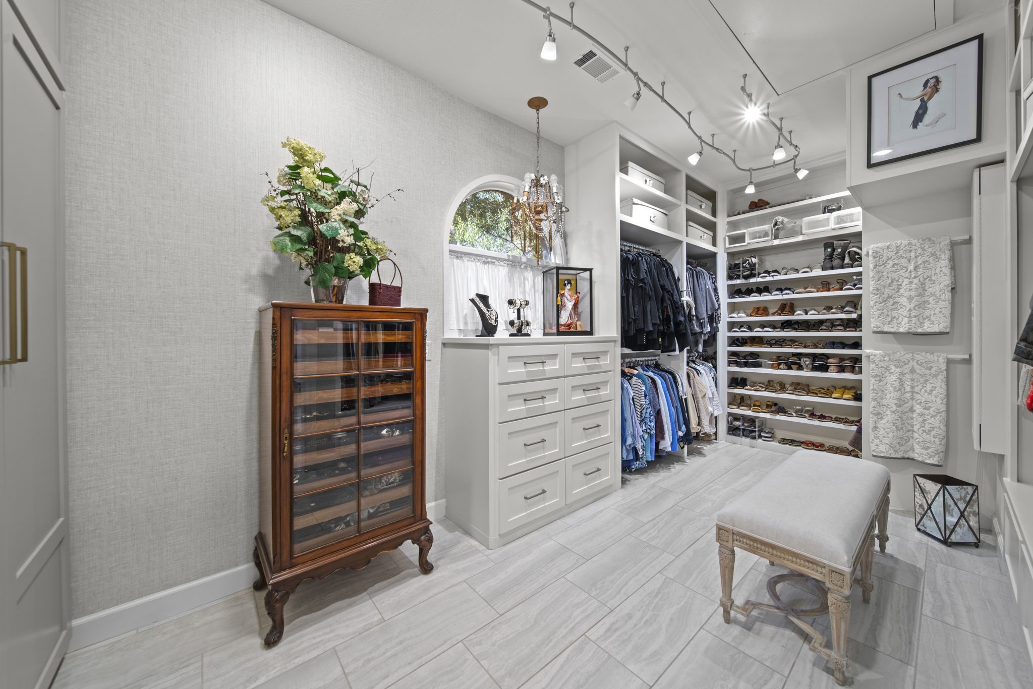 Luxurious closet with lots of space, built-ins galore including a wall ironing board very conveniently placed. Lots of room for your personal items including the custom cabinetry on the left.