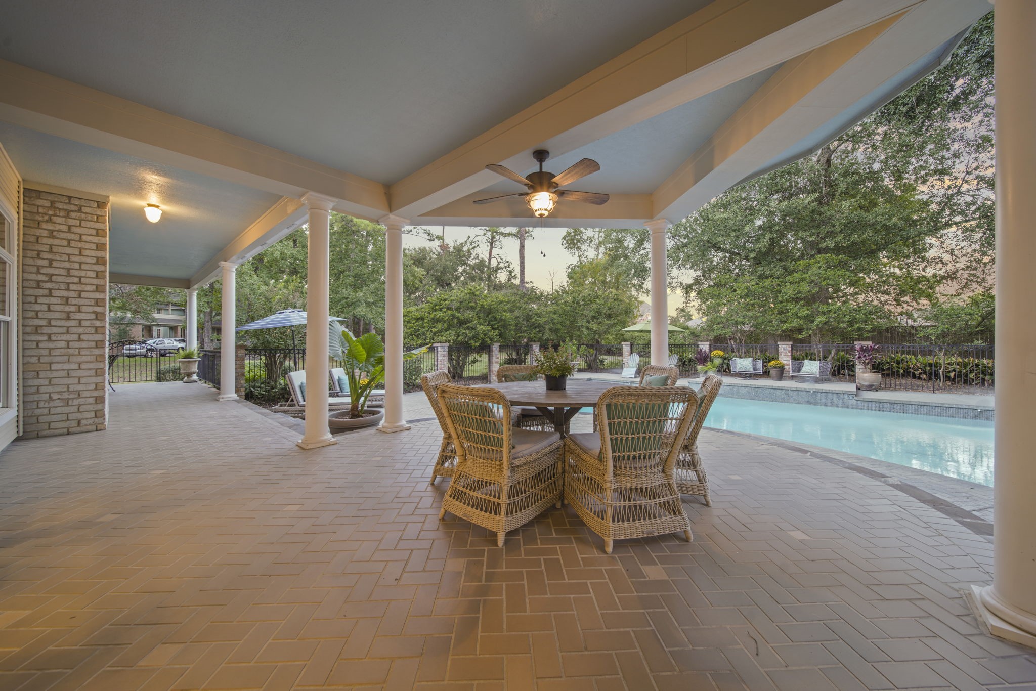 Beautiful outdoor covered area with a ceiling fan & view of the pool.
