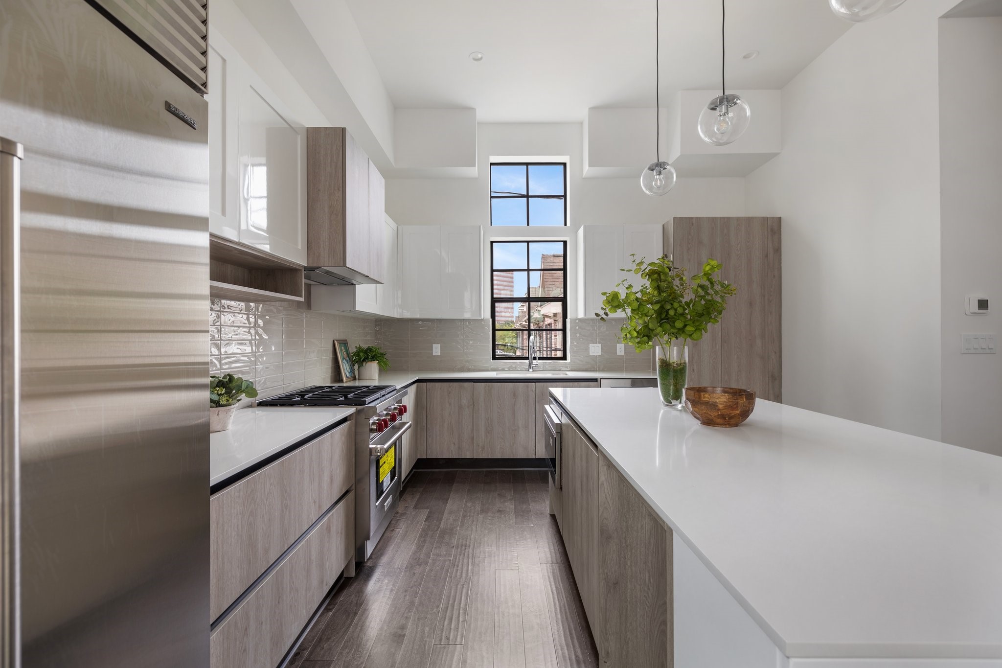 Stunning quartz countertops and imported Contemporary Cabinetry by Madeval blend beauty with durability and are illuminated by luxury island pendants and large windows that filter in natural light.
