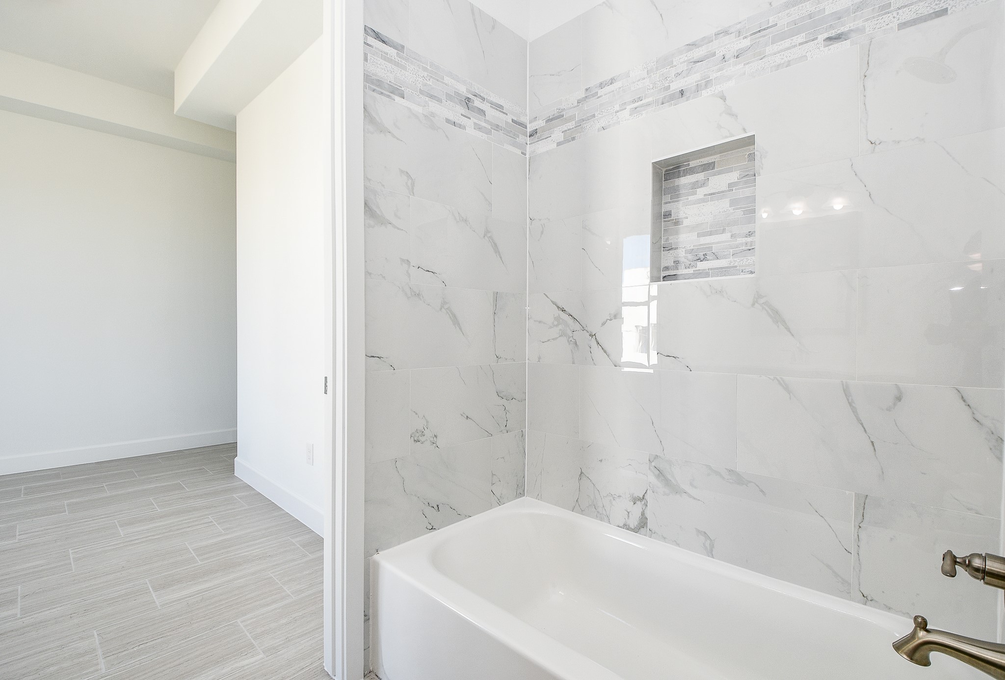 Exquisite marble patterned tile surround and mosaic tile-like accents kick the luxury up a notch in this secondary bathroom.