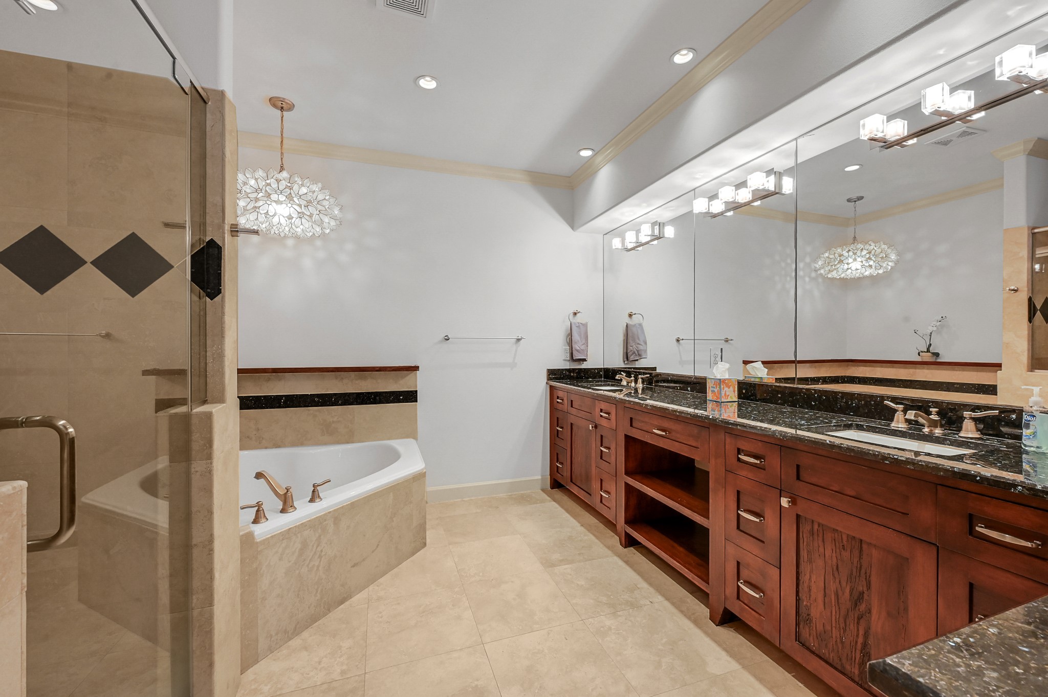 Primary bathroom with travertine flooring, double sinks, walk-in shower, and soaking tub.