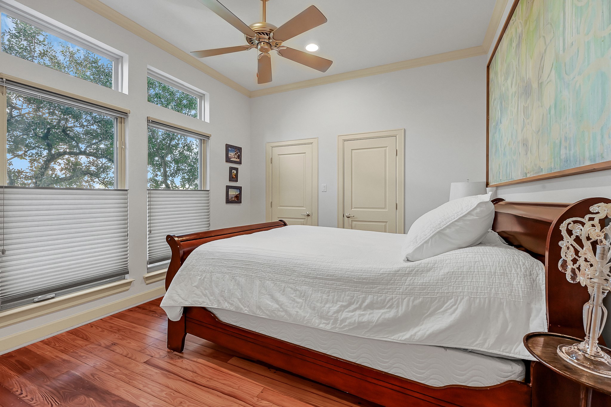 Secondary ensuite bedroom located on third floor with pine floors, high ceilings, and custom shades.