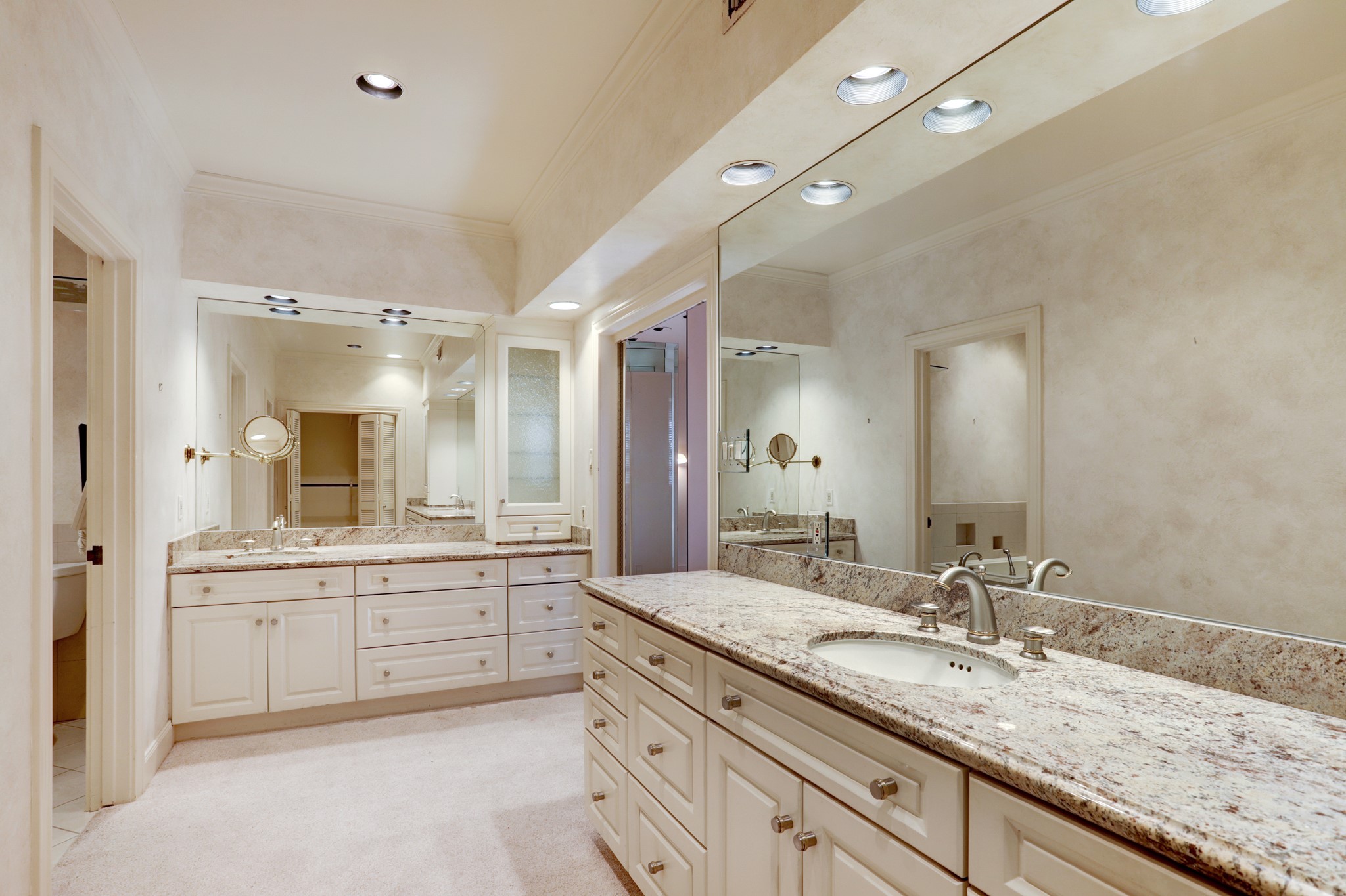 Primary bath with granite counters and two vanities each with drawers and cabinet storage.