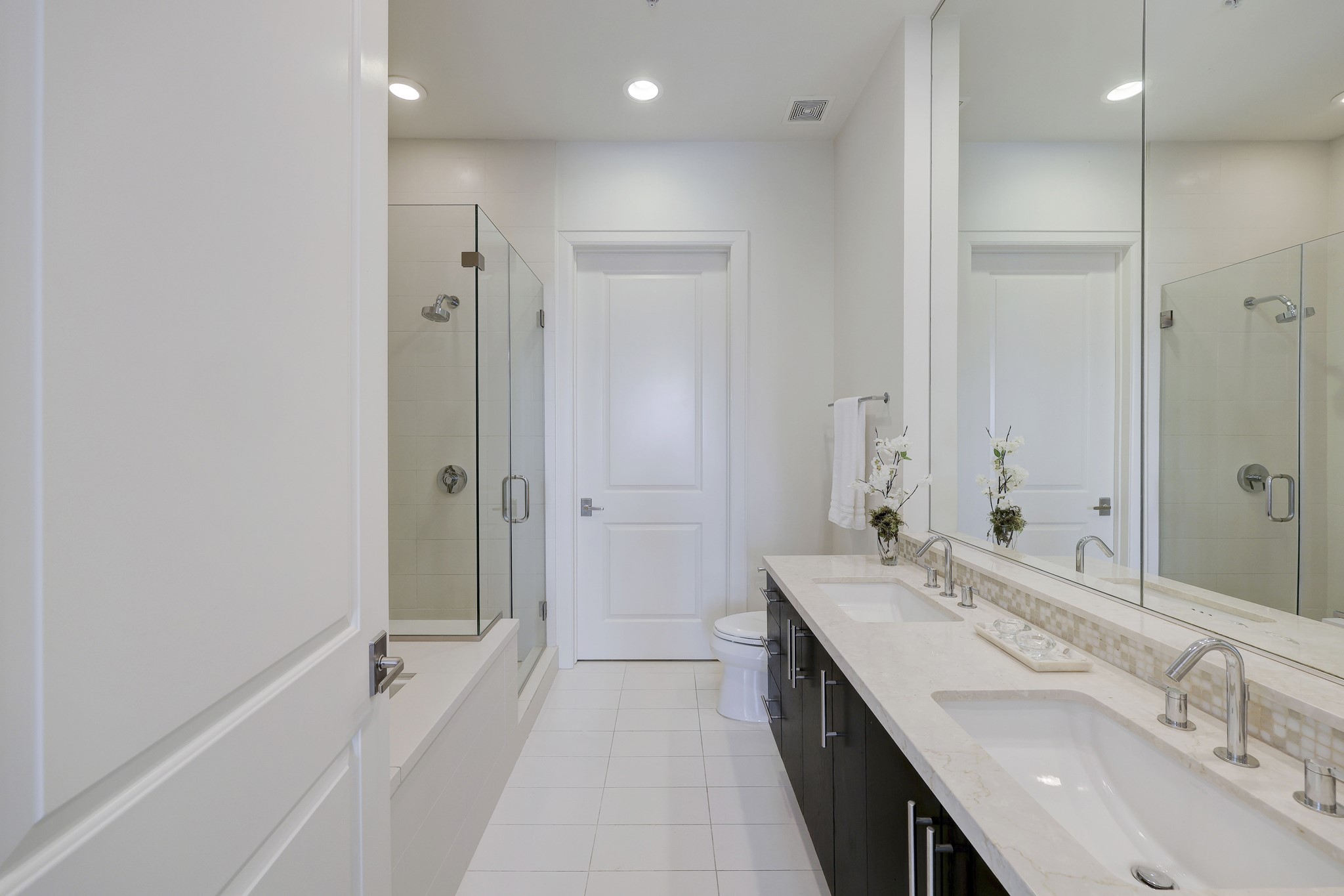 An oversized frameless glass shower and large walk-in closet are at the far end.