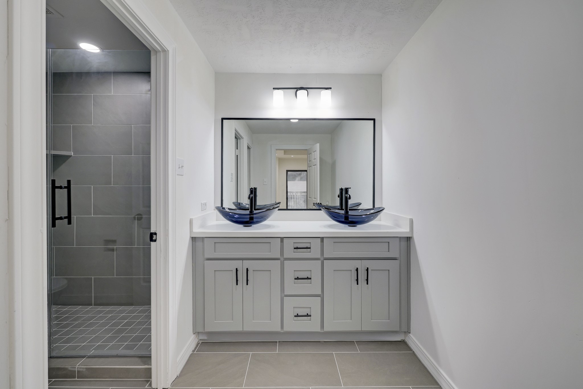 Primary bath with dual vanities and glass-enclosed shower.
