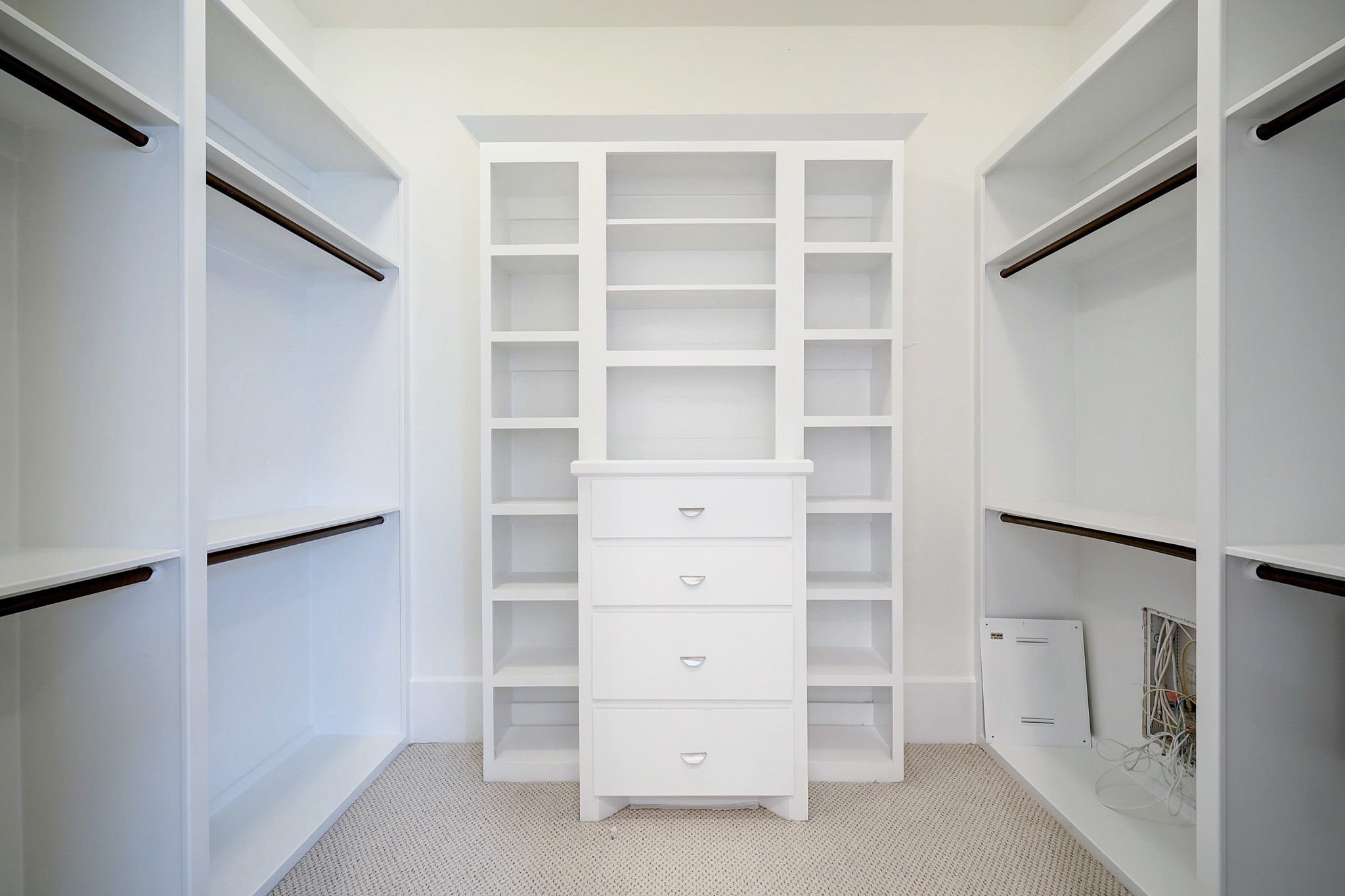 Large walk-in primary closet with built-in storage and plenty of hanging space.
