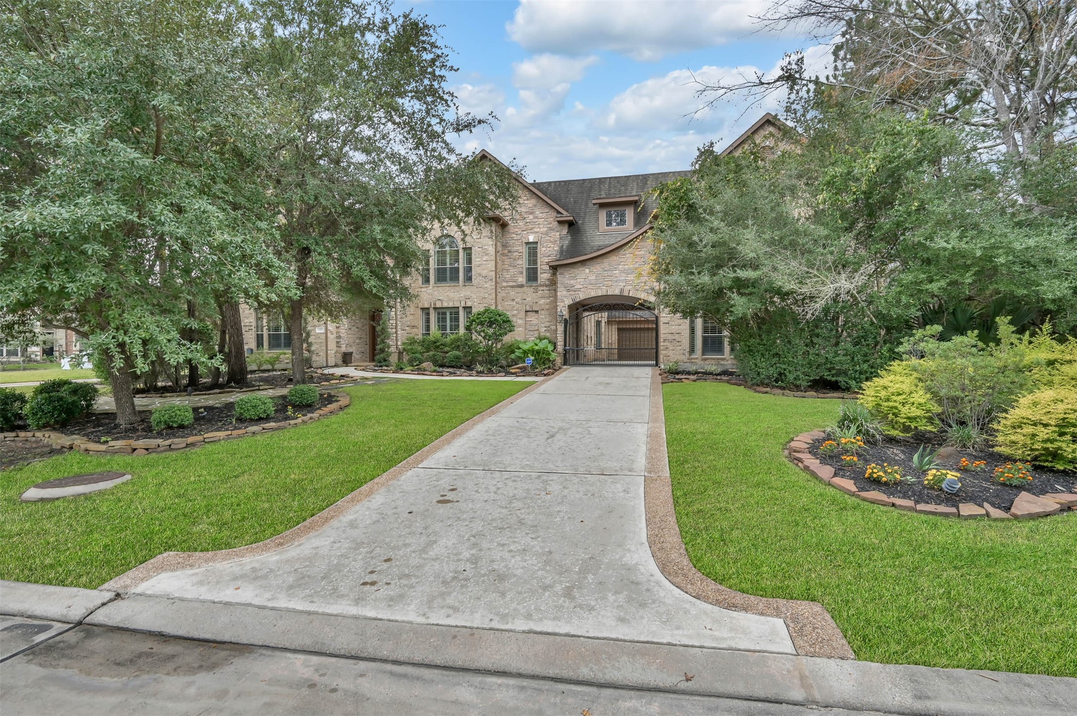 Welcome to 15 Veilwood Circle!  The driveway leads to a gated porte-cochère; a unique feature in the neighborhood. 