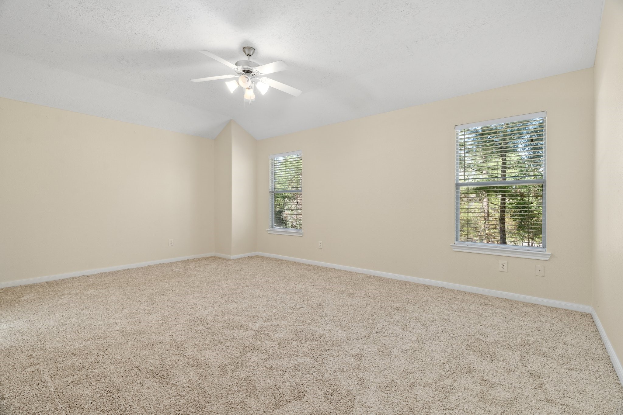 This primary bedroom is spacious and has windows overlooking the backyard.