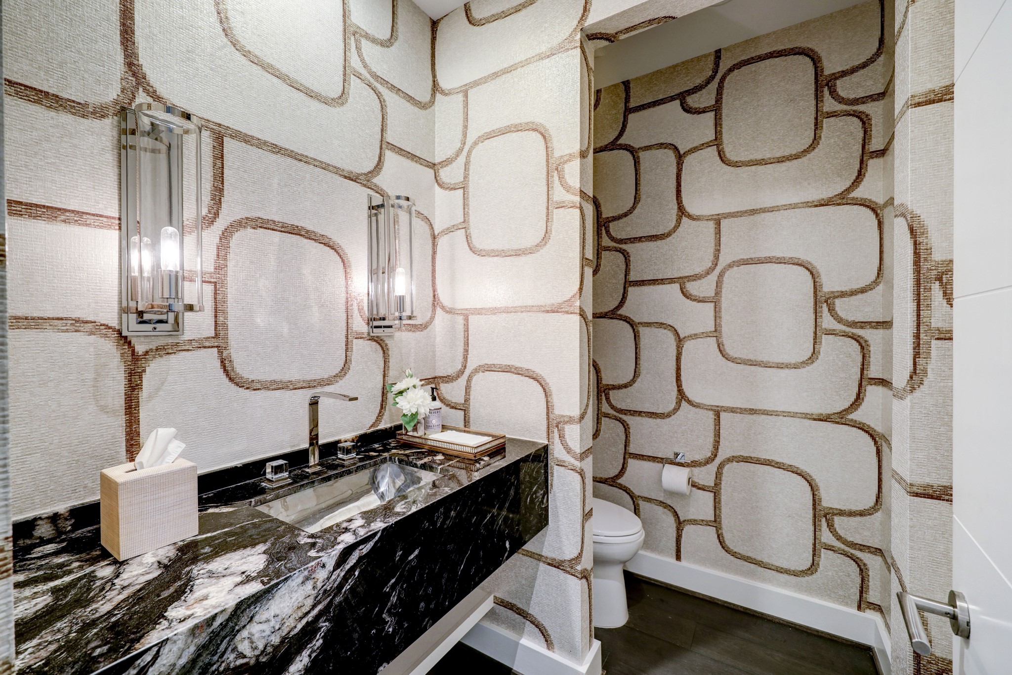 Custom wallpaper, rare marble and designer fixtures and sconces punctuate the powder room.