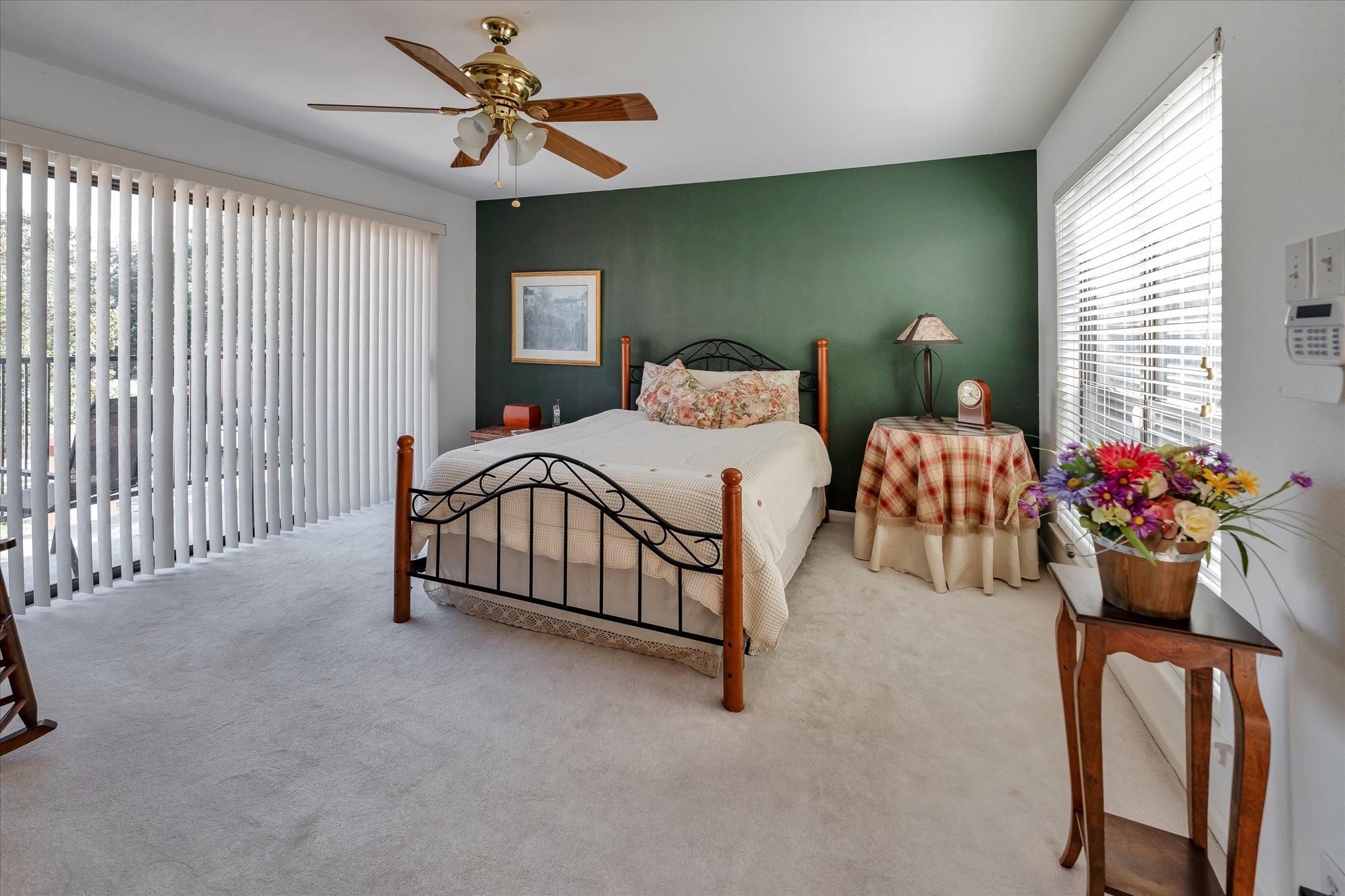 Here's your luxurious primary bedroom located on the 2nd floor, featured by a private balcony, spacious layout and tasteful finishes, with plush carpeting, and large windows framing views of the outdoor greenery.