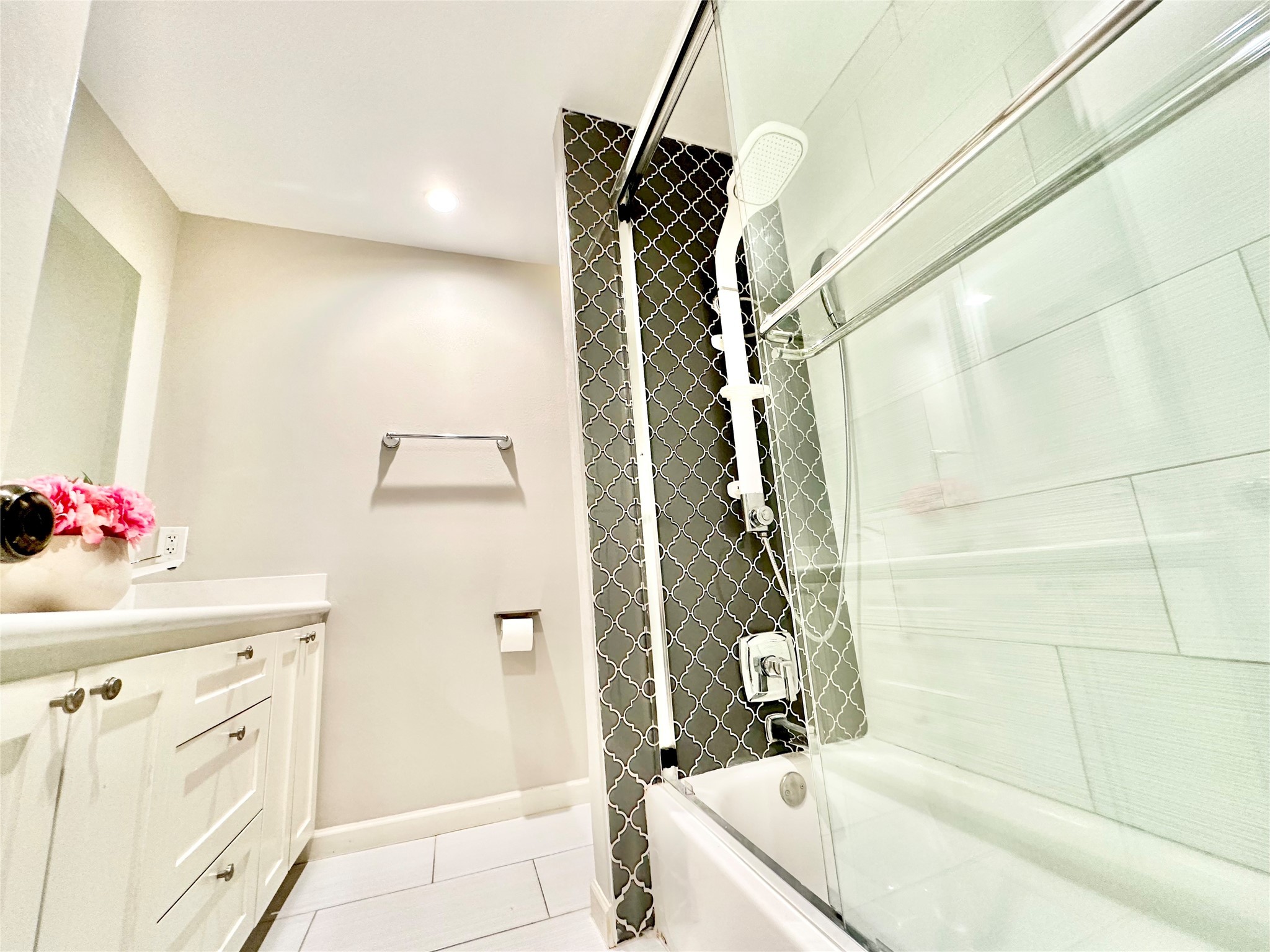 Fully remodeled hall bathroom with quartz counter, white cabinets, ceramic tile floor and a fancy contemporary shower.