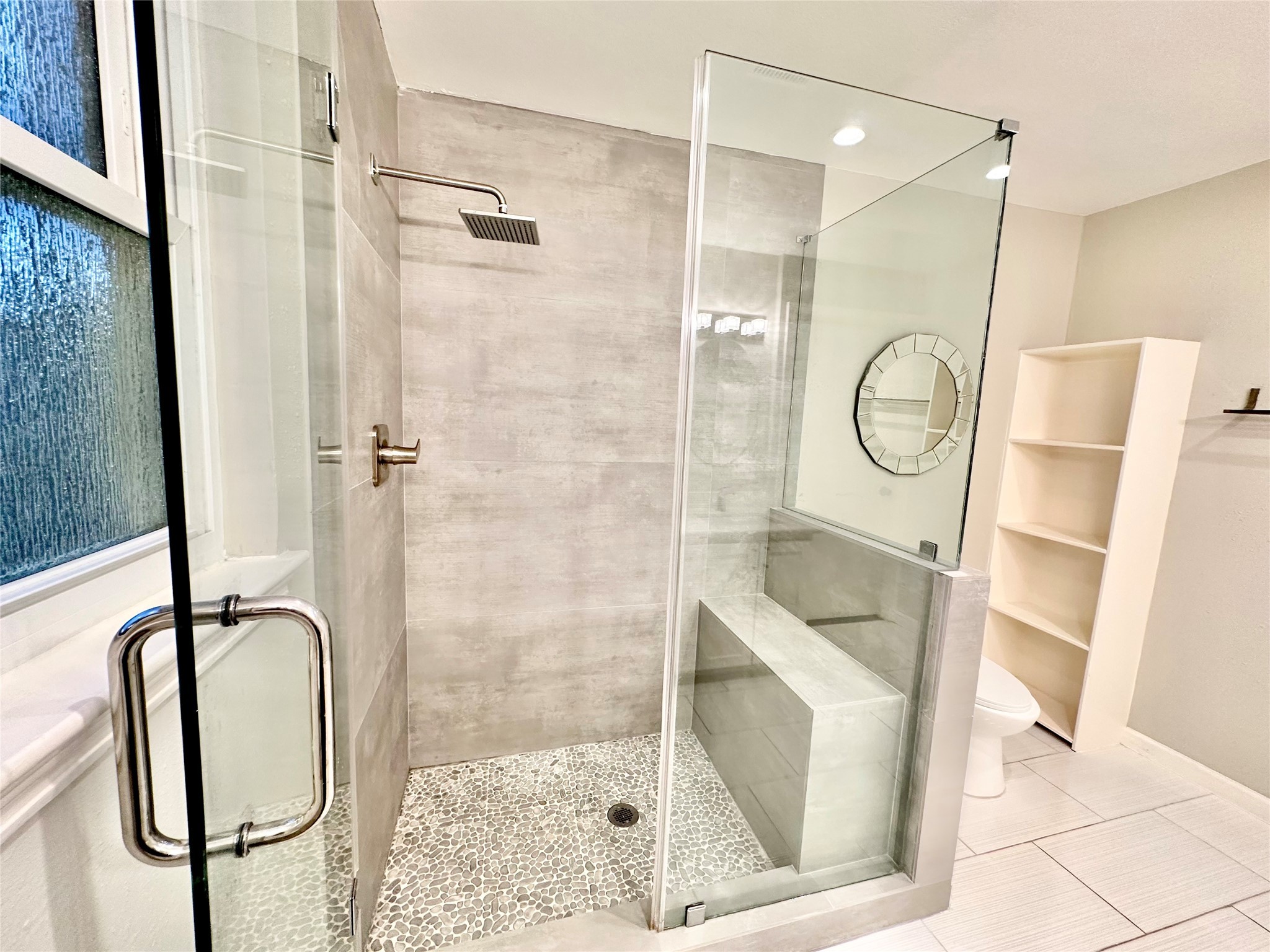 Take a refreshing rinse in the newly updated rimless glass enclosed shower with luxurious floor tile work and surround tiles all the way to the top and a comfy bench.