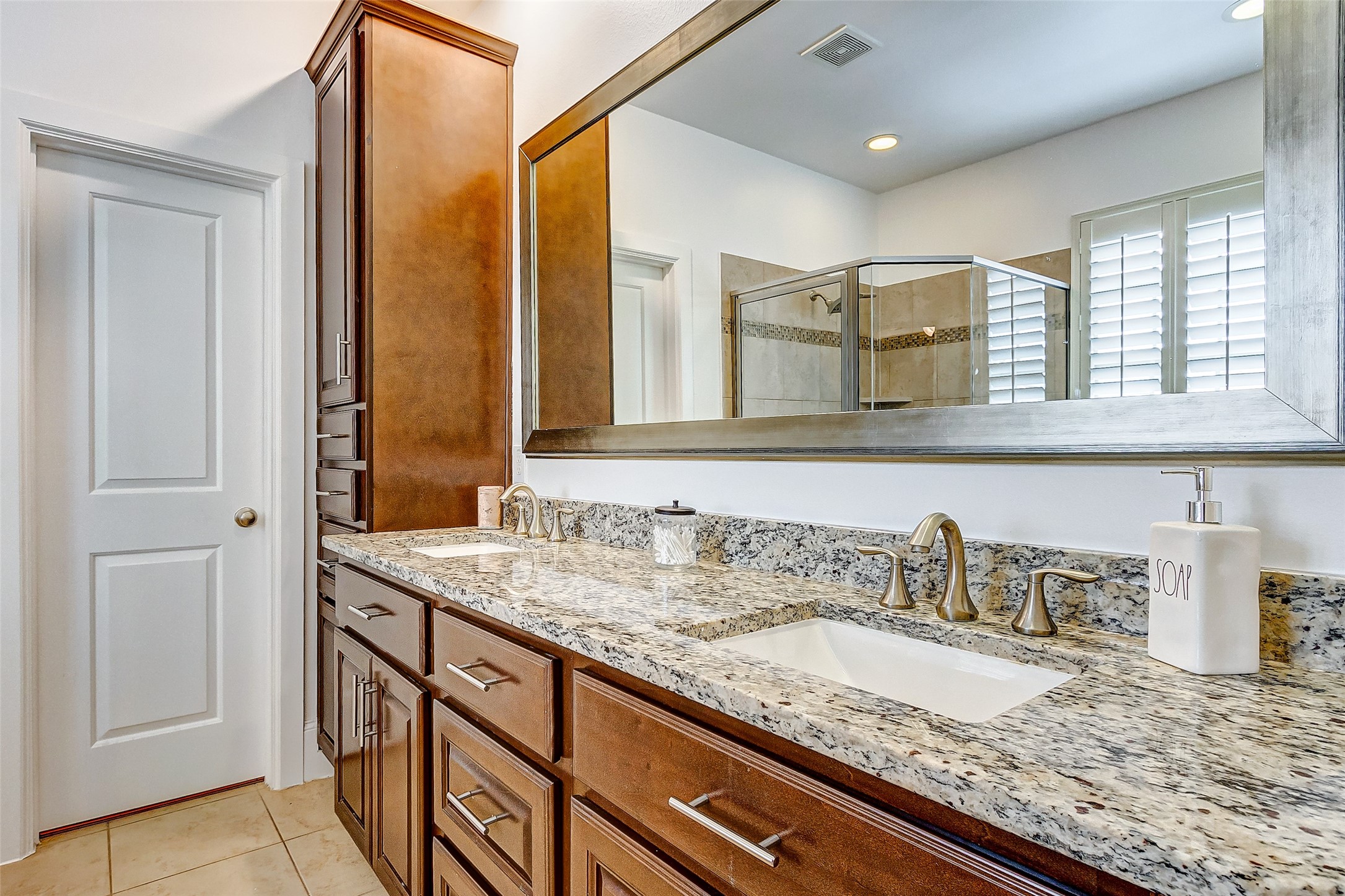 Your stunning primary ensuite bathroom features granite countertops, dual sinks, rich vanity cabinetry, oversized framed mirror, and plentiful storage space!
