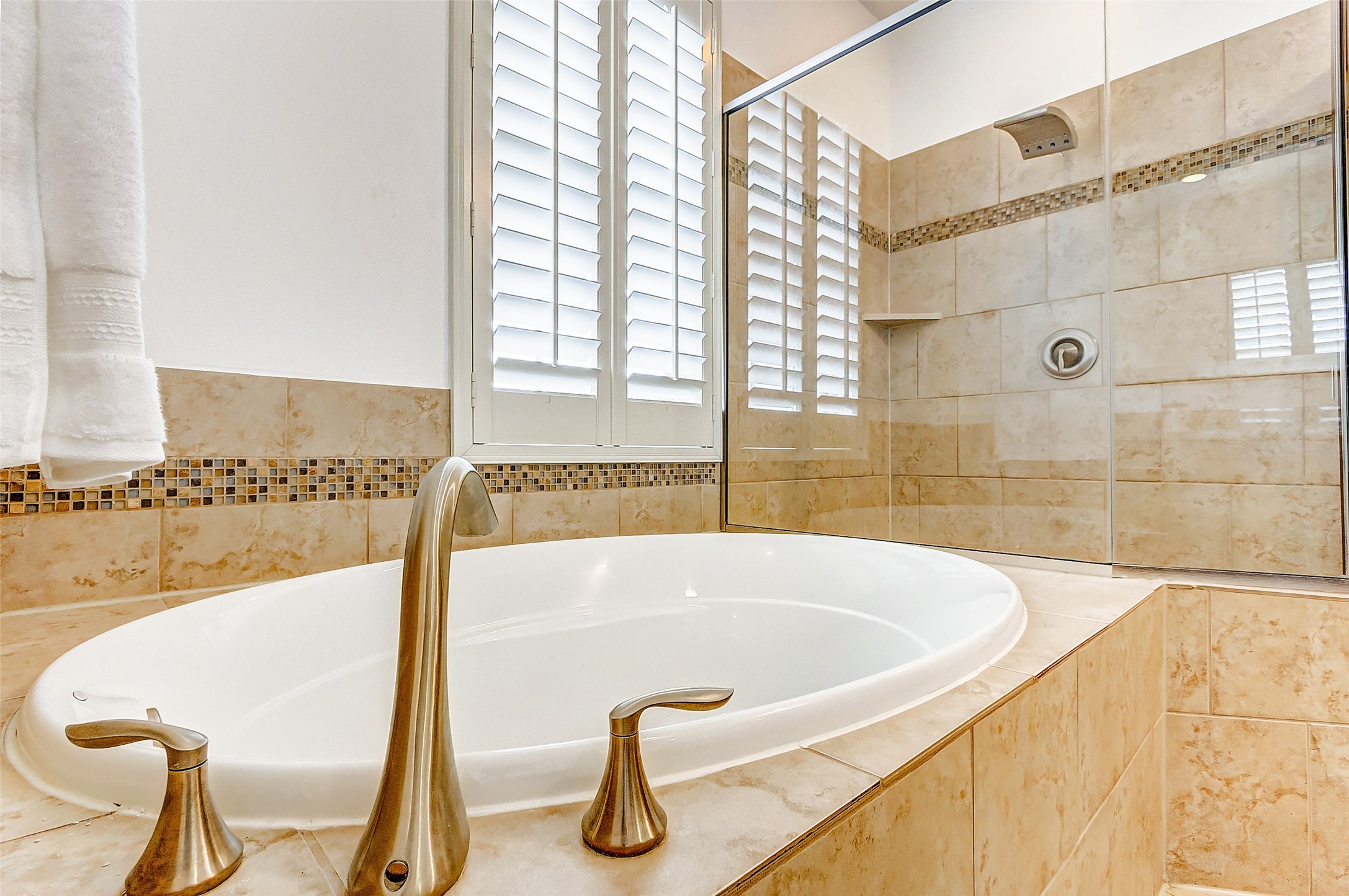 Your new garden tub sits beneath an obscure window lined with custom plantation shutters that allows for natural light without compromising privacy.