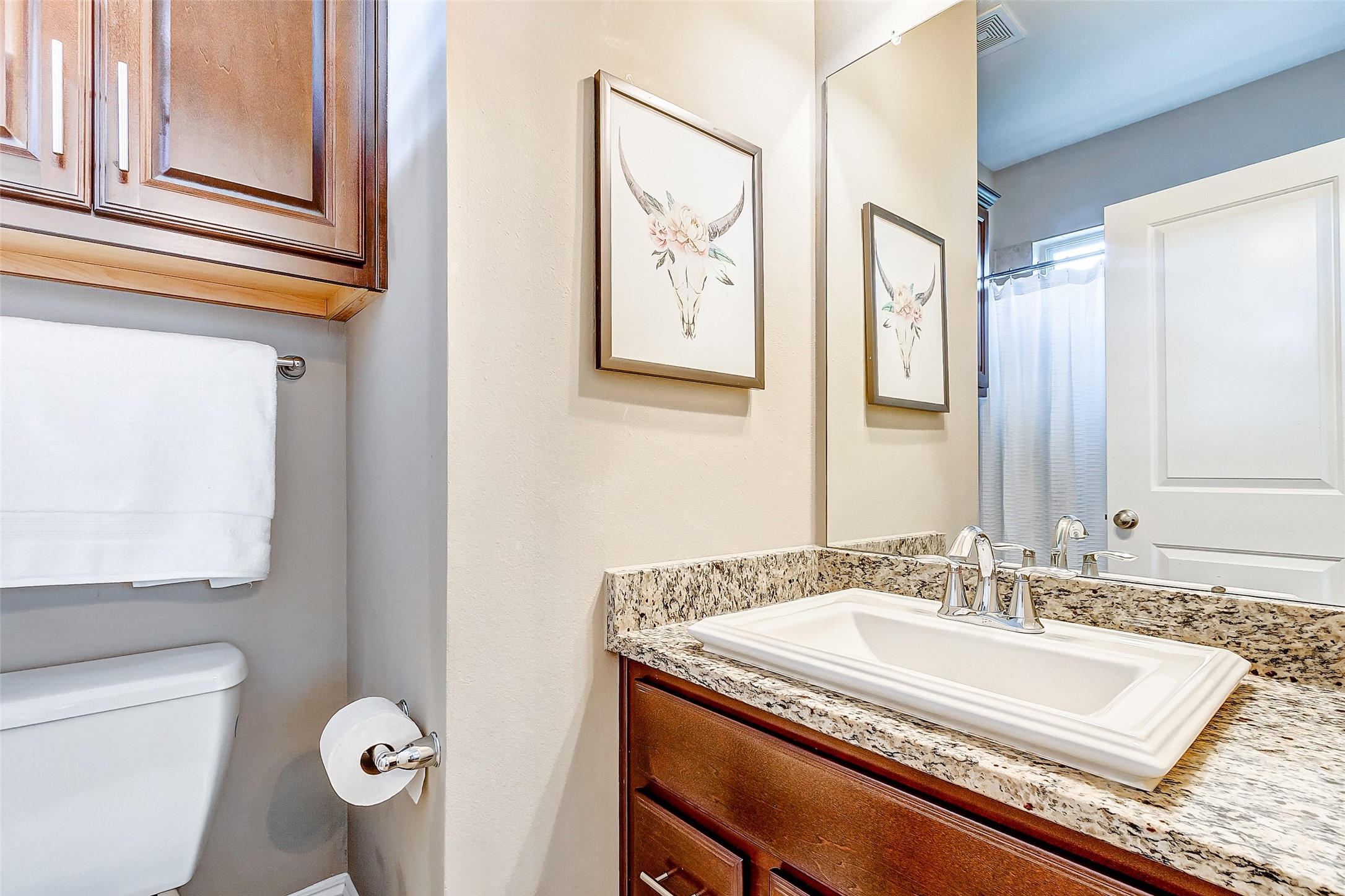 The third floor secondary bathroom boasts granite counters, neutral paint, rich cabinetry, brushed nickel pulls, and tub/shower combo.