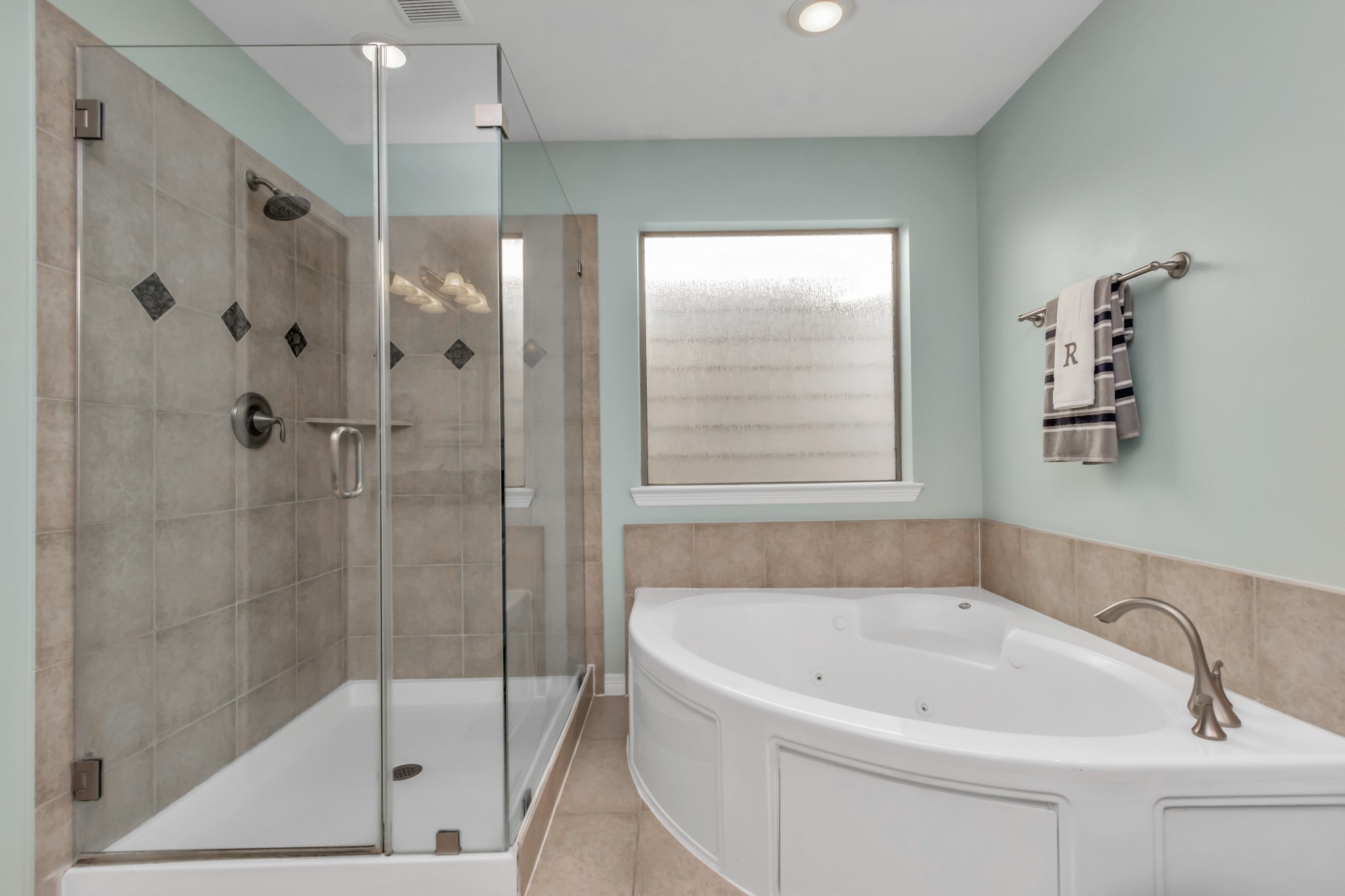 An immense seamless glass shower is not only useful but also brings a sense of beauty to this bathroom. Indulge in leisurely soaks with the generously sized corner tub, providing the perfect setting for relaxation.