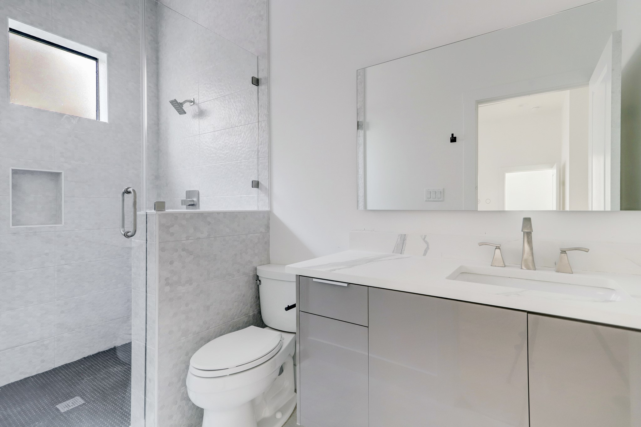 En suite bath with glass enclosed shower and contemporary design.