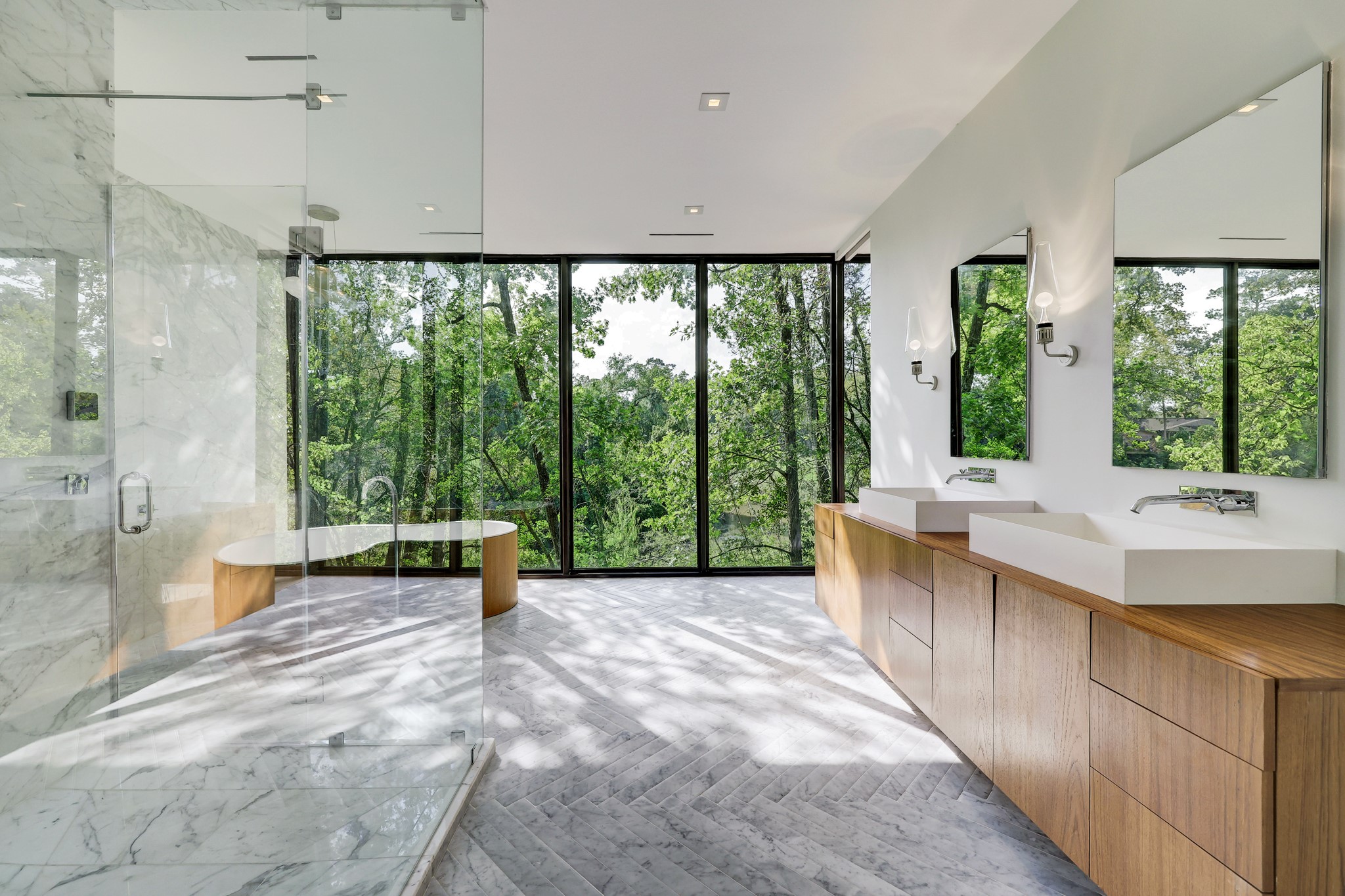 [Primary Bath]
The Zen-inspired bath offers a herringbone-pattern marble tile floor; floating teak cabinets with vessel sinks; a free-standing, amoeba-shaped bathtub with floor-mounted faucet; a seamless-glass, teak, and marble steam shower; and a private water closet.